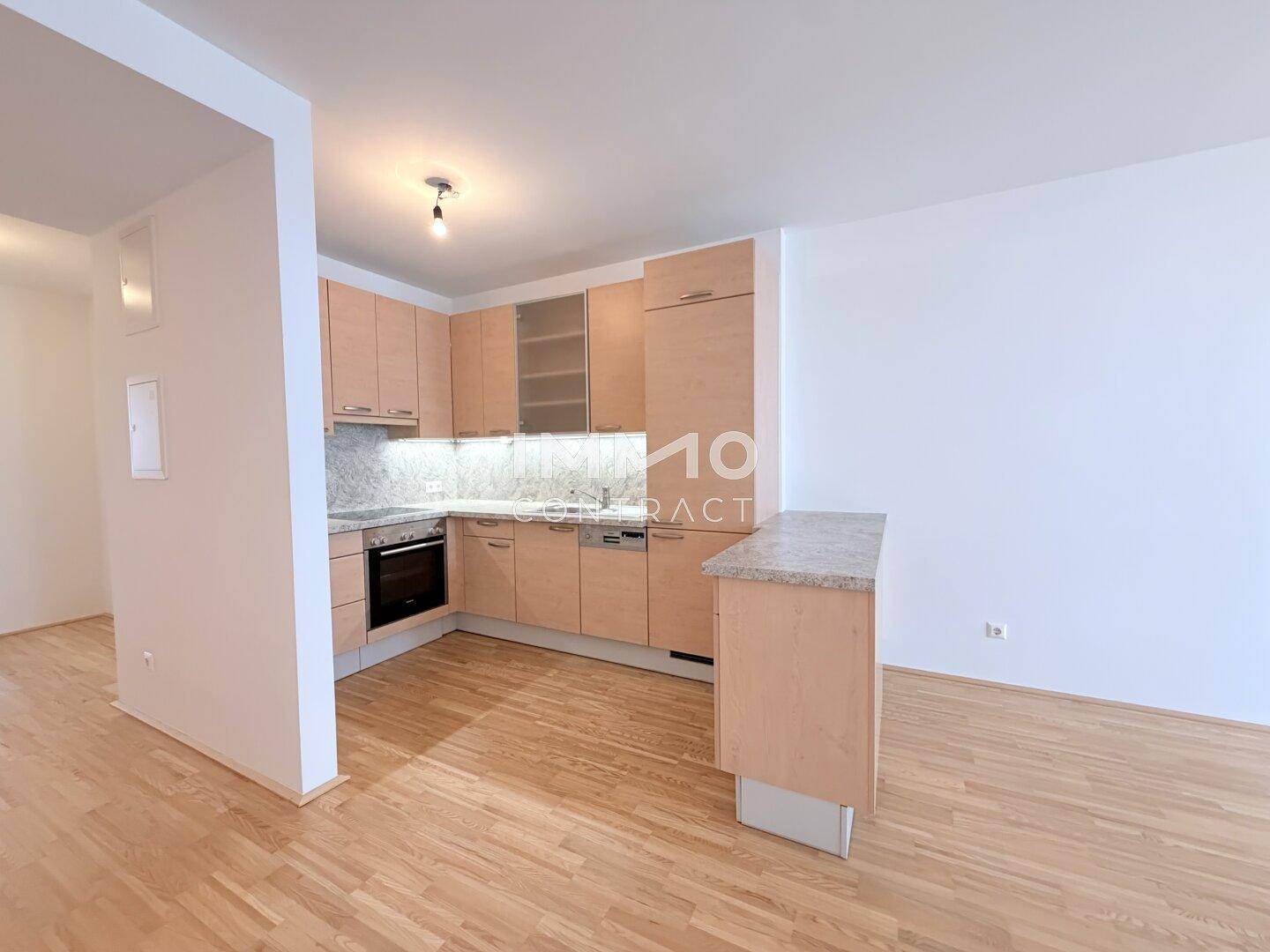 Helle Küchenzeile mit Holzschränken und Granit-Arbeitsplatte, offen zum Wohnbereich.