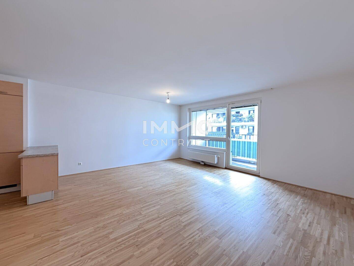 Helles Wohnzimmer mit Parkettboden und großen Fenstern, die viel Tageslicht hereinlassen.