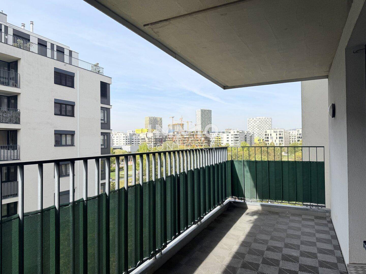 Balkon mit Blick auf die Stadt und umliegende Gebäude, ausgestattet mit praktischem Bodenbelag.