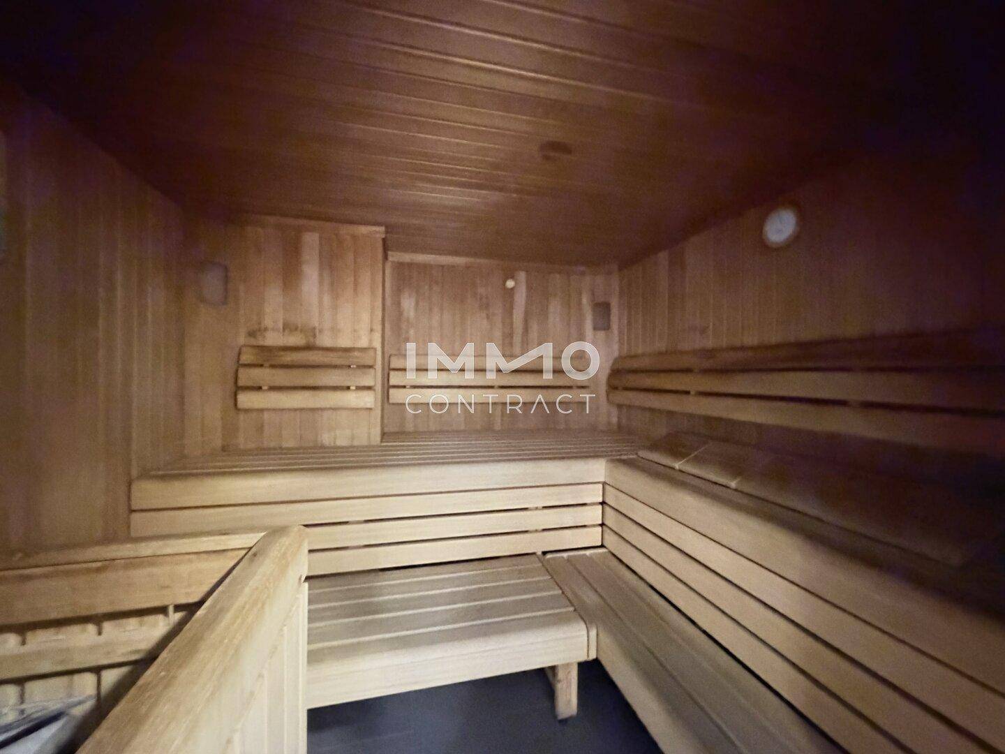 Traditionelle Saunakabine mit dunklem Holz und gestuften Bänken für mehrere Personen.