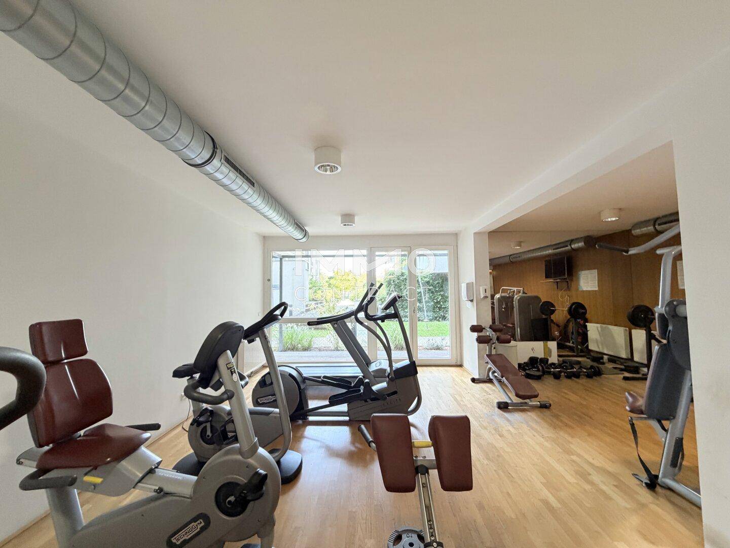 Heller Fitnessbereich mit modernen Trainingsgeräten und direktem Zugang zum Außenbereich.