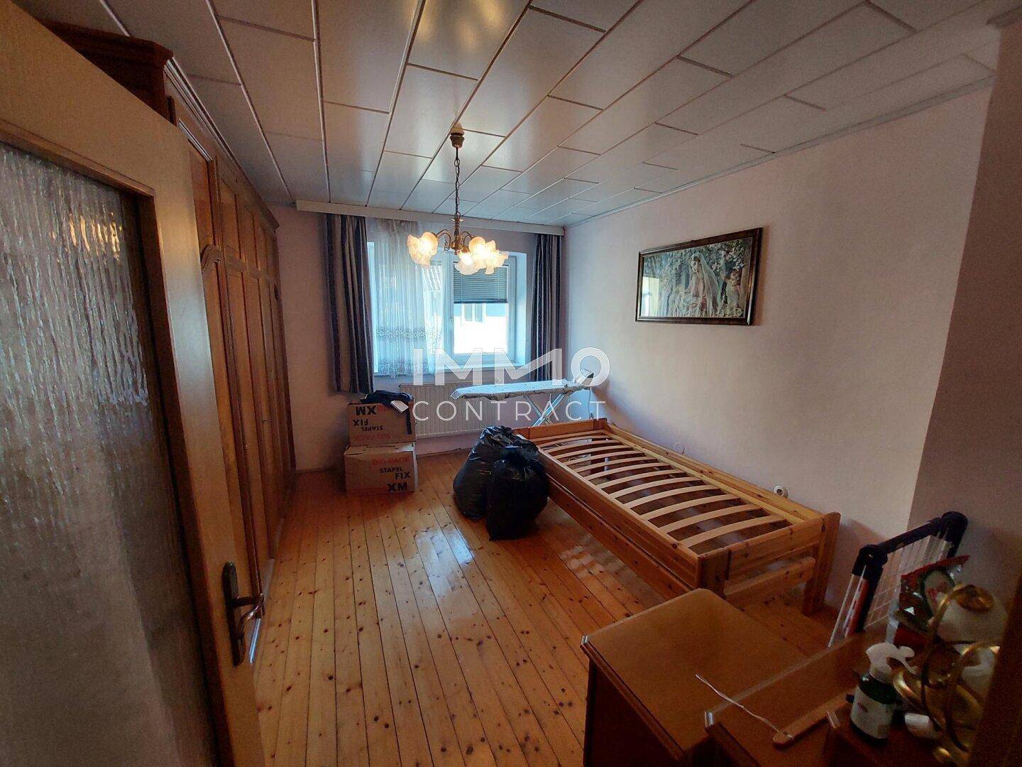 Schlafzimmer mit Holzboden, Holzdecke und einem Einzelbett, bereit zur Einrichtung.