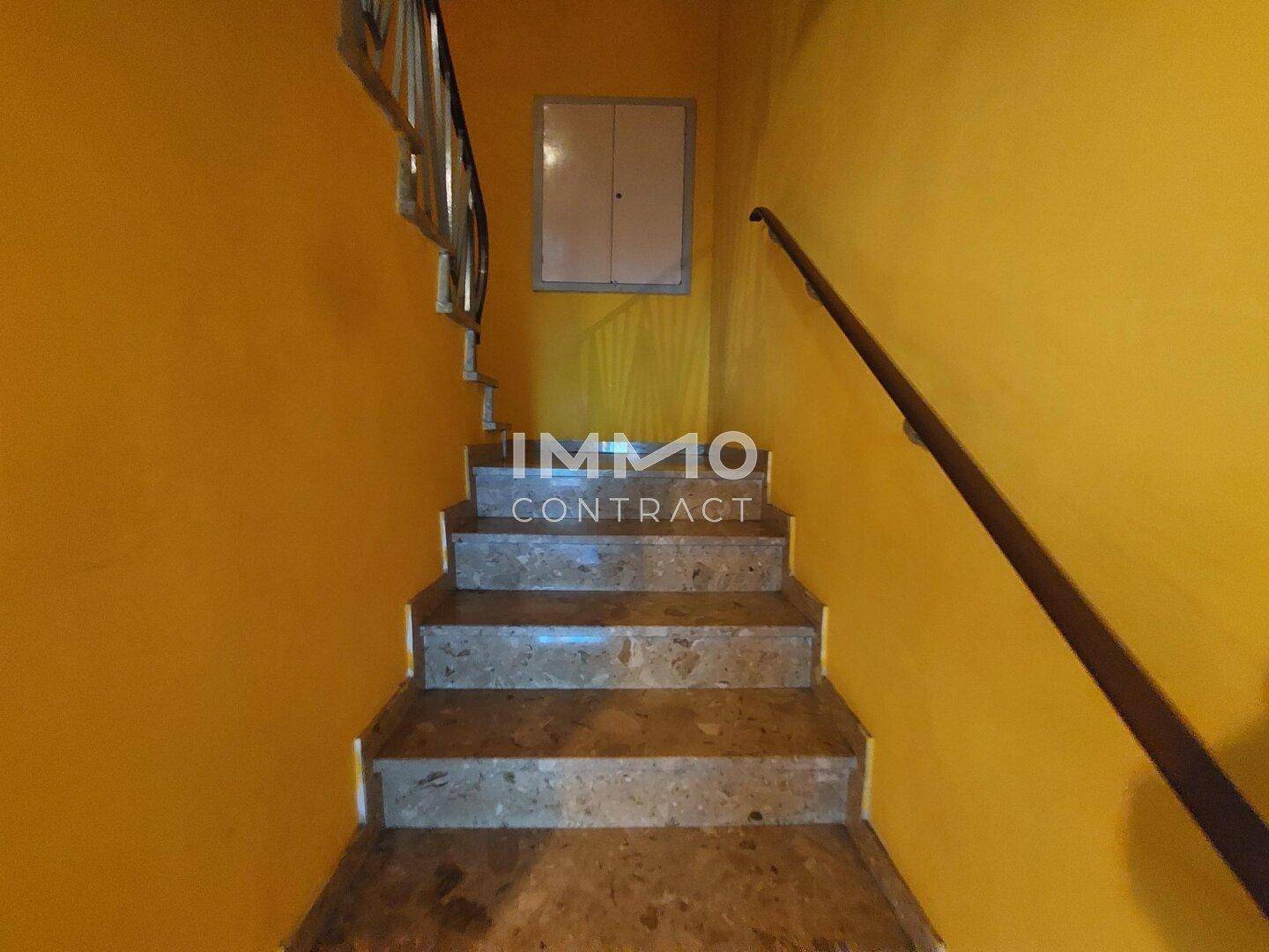 Treppenhaus mit Steinstufen und gelb gestrichenen Wänden, führt in die obere Etage.