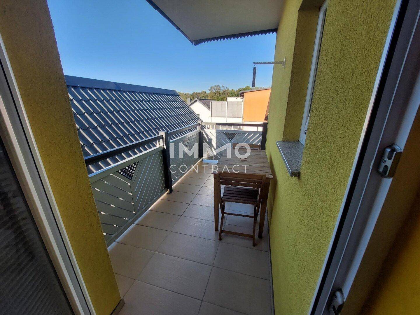 Schmaler Balkon mit Fliesenboden und Metallgeländer, ideal für einen kleinen Tisch.