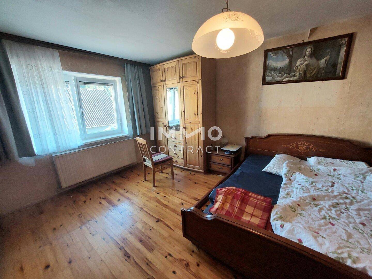 Schlafzimmer mit Holzboden, traditioneller Einrichtung und Fenster für Tageslicht.