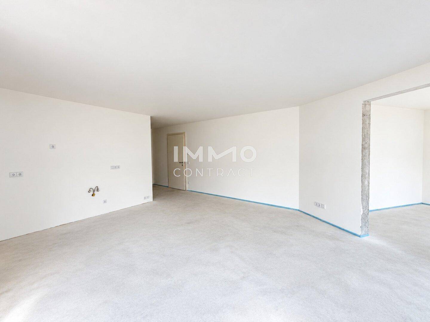 Großer, unmöblierter Raum mit weißen Wänden und Betonboden, bereit für den Innenausbau.
