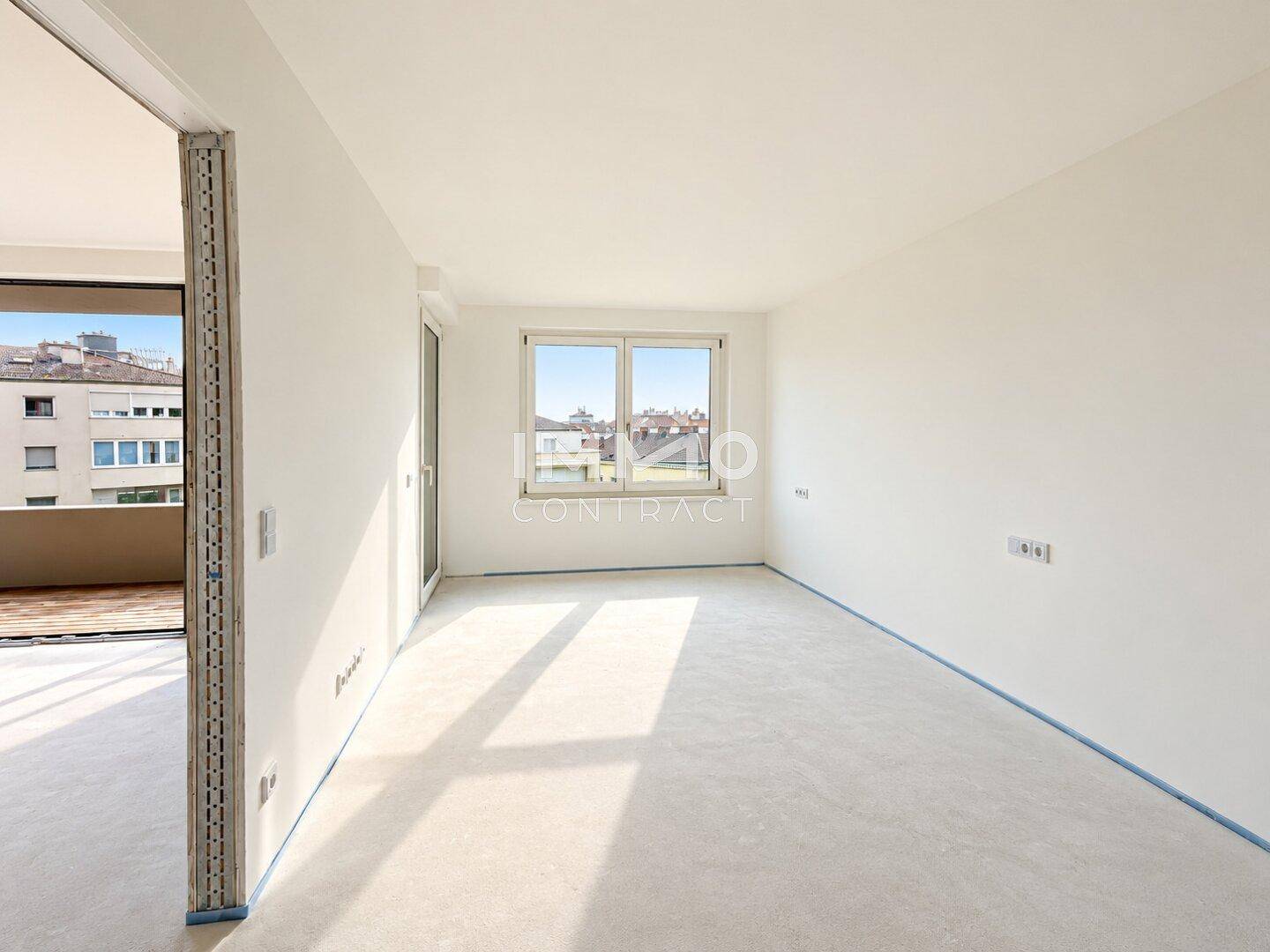 Heller, unmöblierter Raum mit großem Fenster und Zugang zu einem Außenbereich.