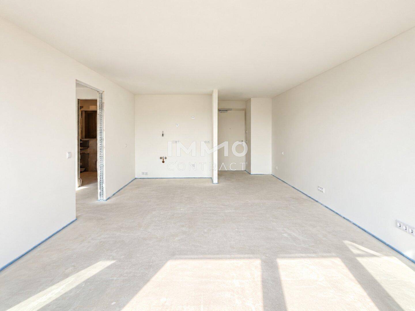Unmöblierter Innenraum mit Rohbau-Boden und vorbereiteten Wänden, bereit für den Ausbau.