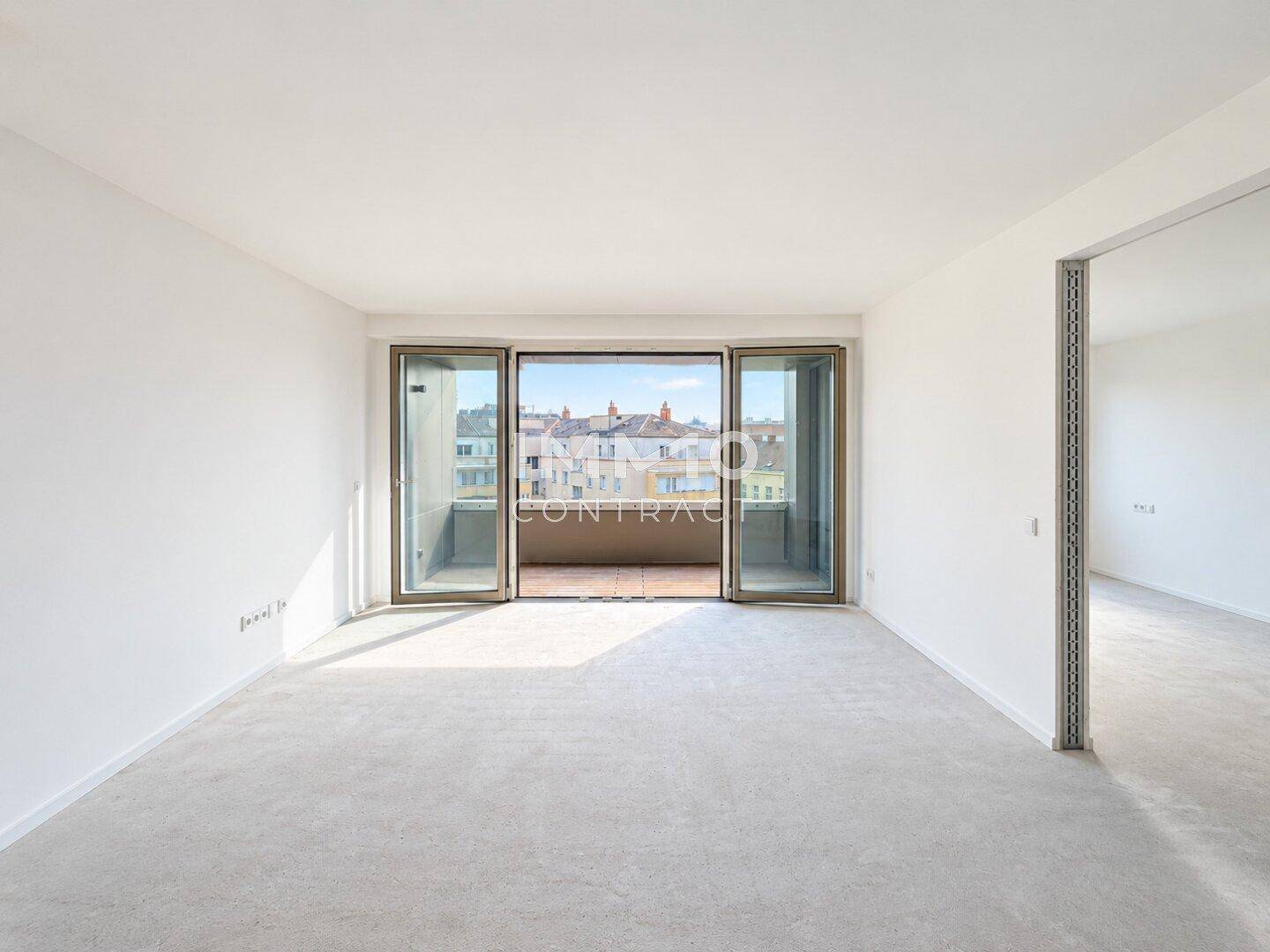 Heller, unmöblierter Wohnraum mit Zugang zu einem Balkon und Blick auf die Stadt.