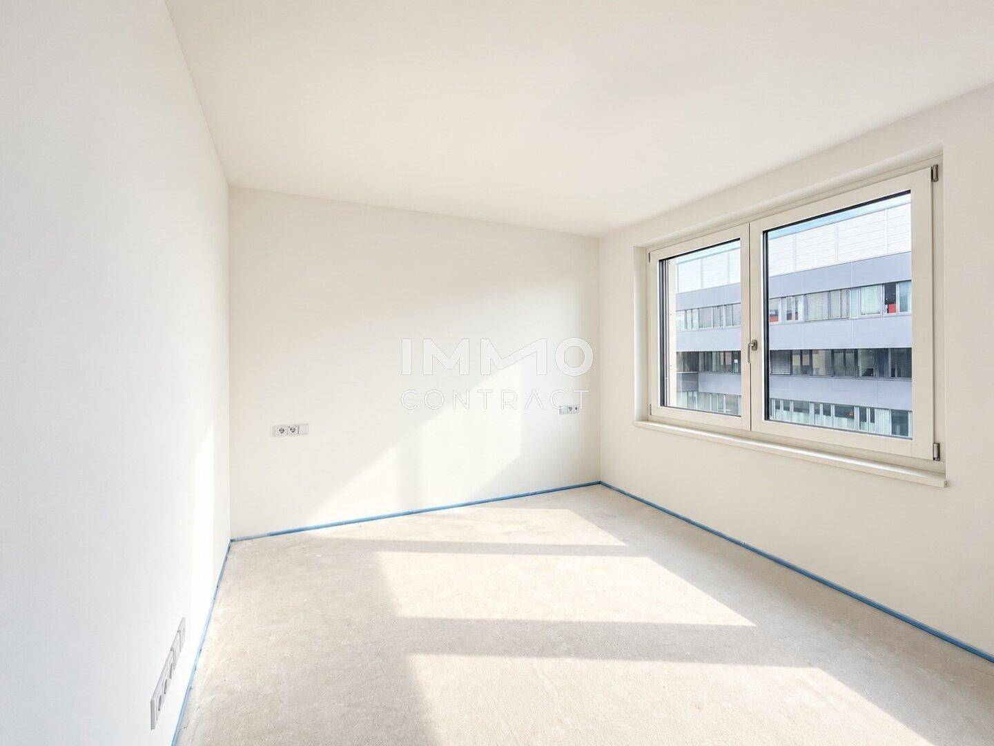 Leeres Zimmer mit weißen Wänden und Fenster, vorbereitet für die Bodengestaltung, bietet viel Tageslicht.