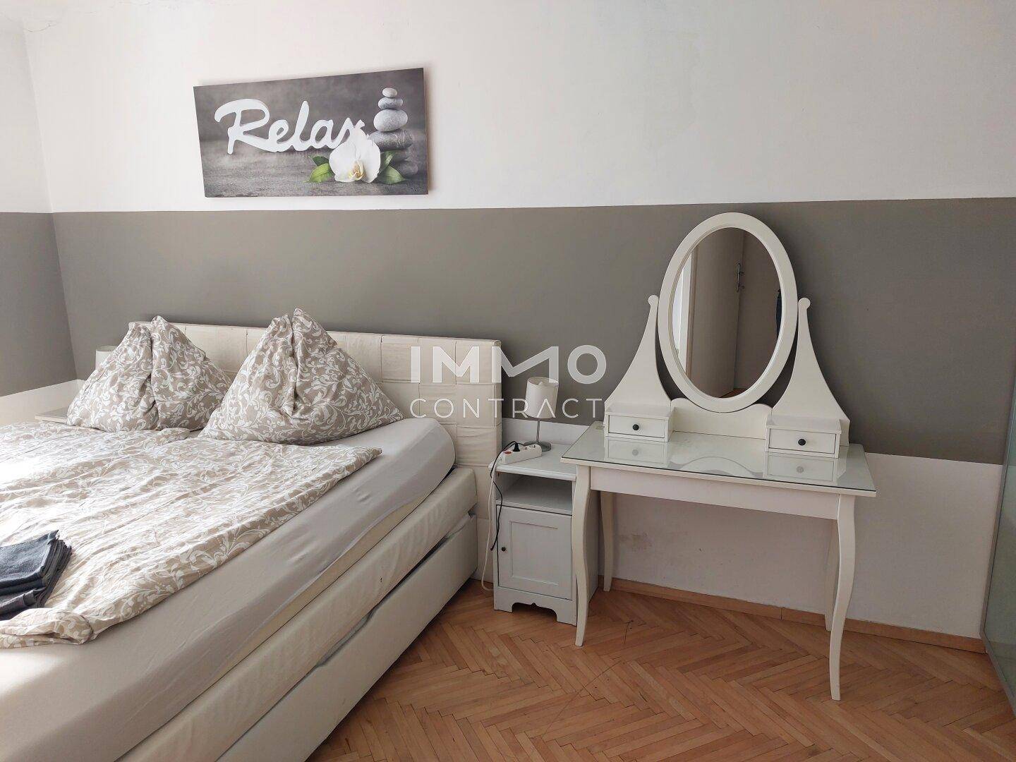 Gemütliches Schlafzimmer mit Doppelbett, Schminktisch und Fischgrätparkettboden.
