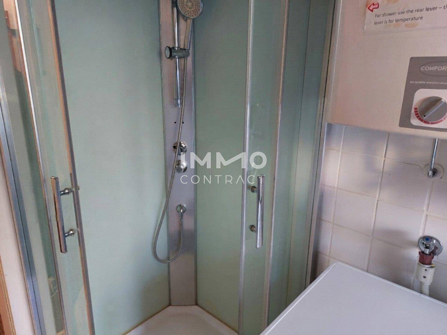 Duschkabine mit Duschpaneel und weiß gefliesten Wänden im Badezimmer.