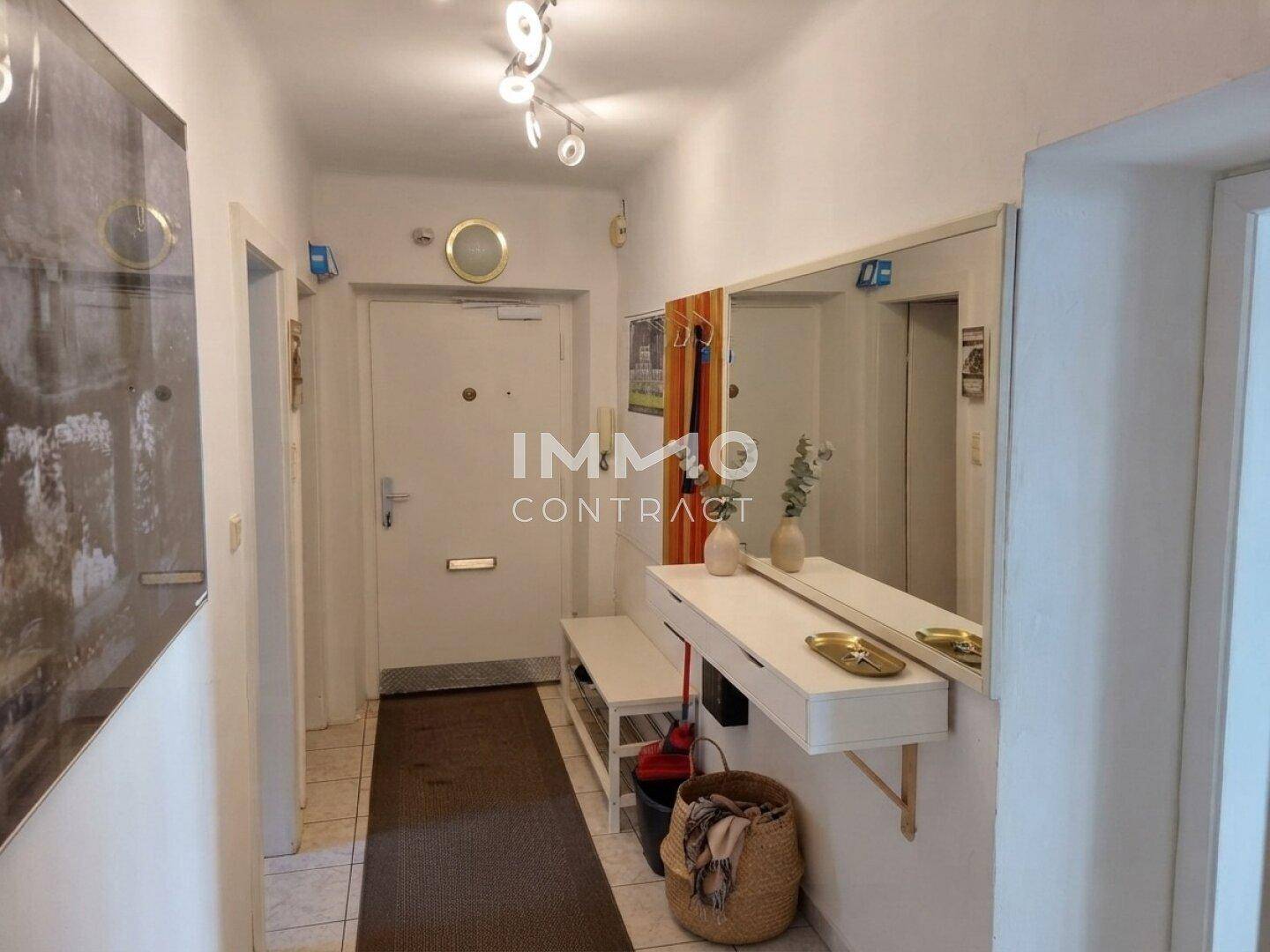 Eingangsbereich mit Garderobe, großem Spiegel und Fliesenboden.
