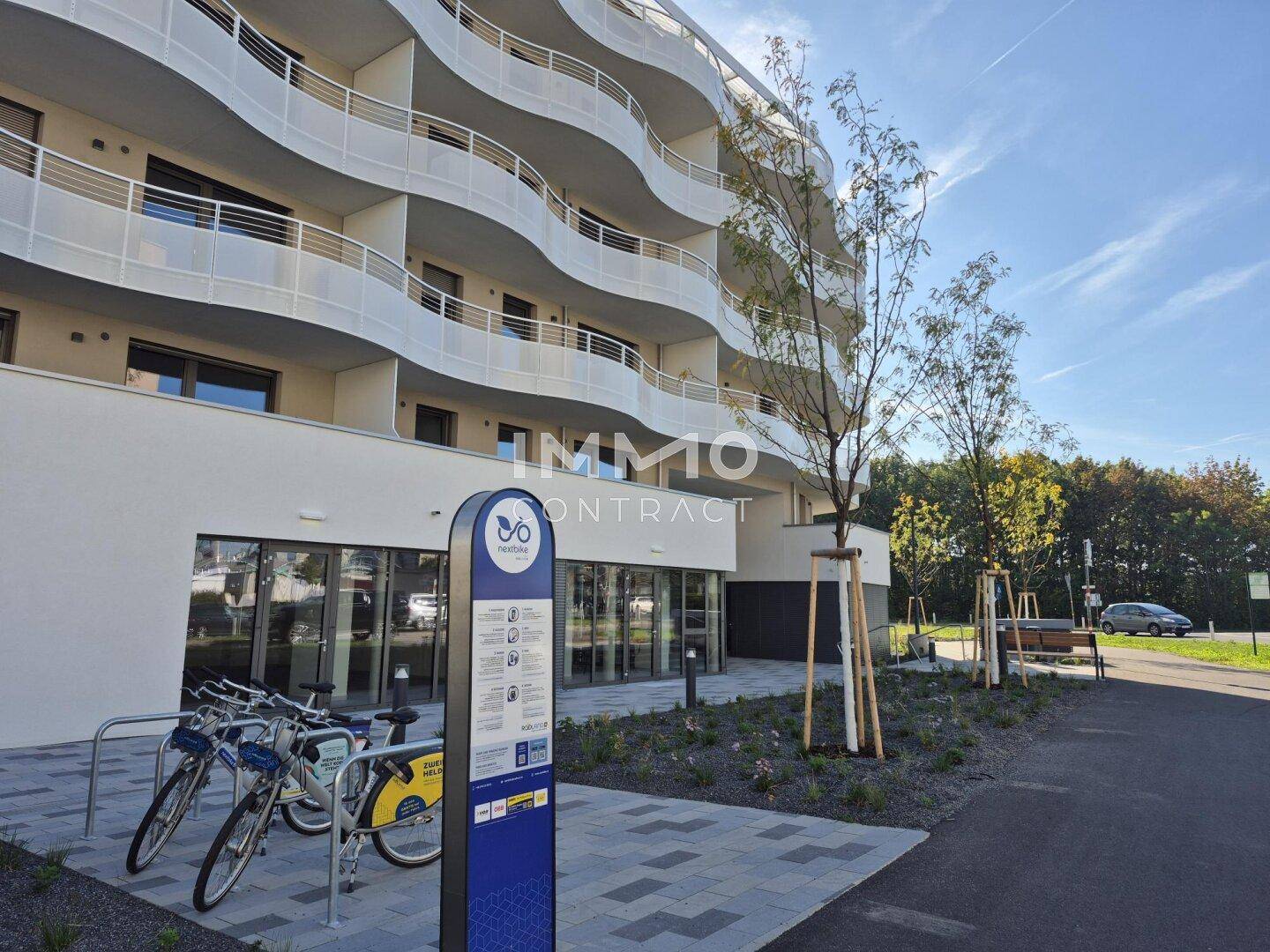 Ansicht des modernen Gebäudes mit einer Fahrradverleihstation im Vordergrund.