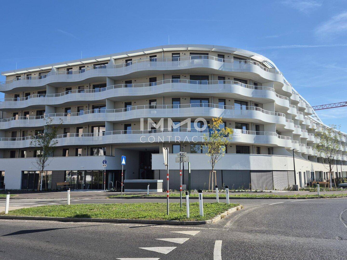 Großes, modernes Apartmentgebäude mit geschwungenen Balkonen und zeitgenössischer Architektur.