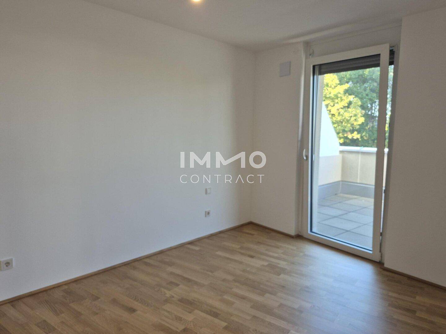 Helles Schlafzimmer mit Parkettboden und Zugang zu einem Balkon oder einer Terrasse.