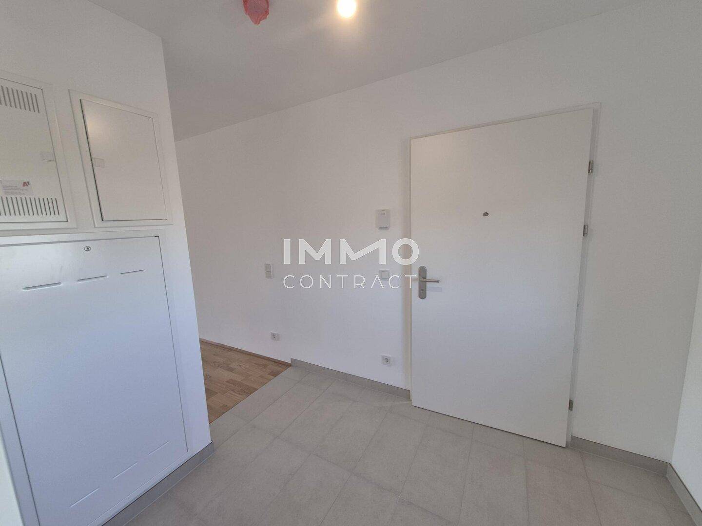 Eingangsbereich mit Fliesenboden, weiß gestrichenen Wänden und Zugang zur Wohnung.