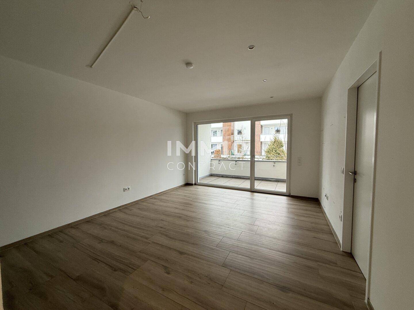 Helles Wohnzimmer mit Zugang zu einem Balkon und Blick auf die Umgebung.