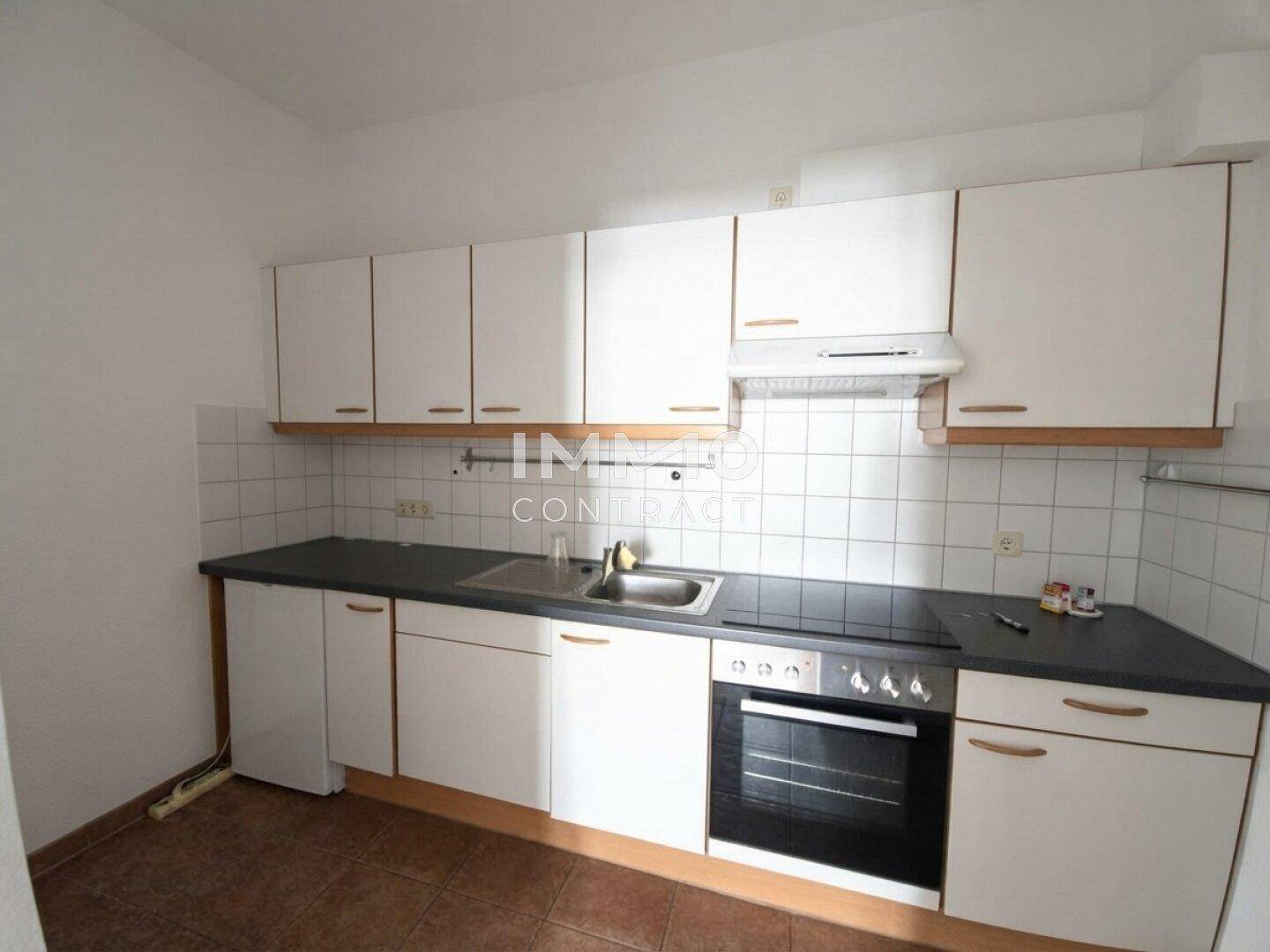 Funktionale Küche mit weißen Schränken, dunkler Arbeitsplatte und gefliestem Spritzschutz.