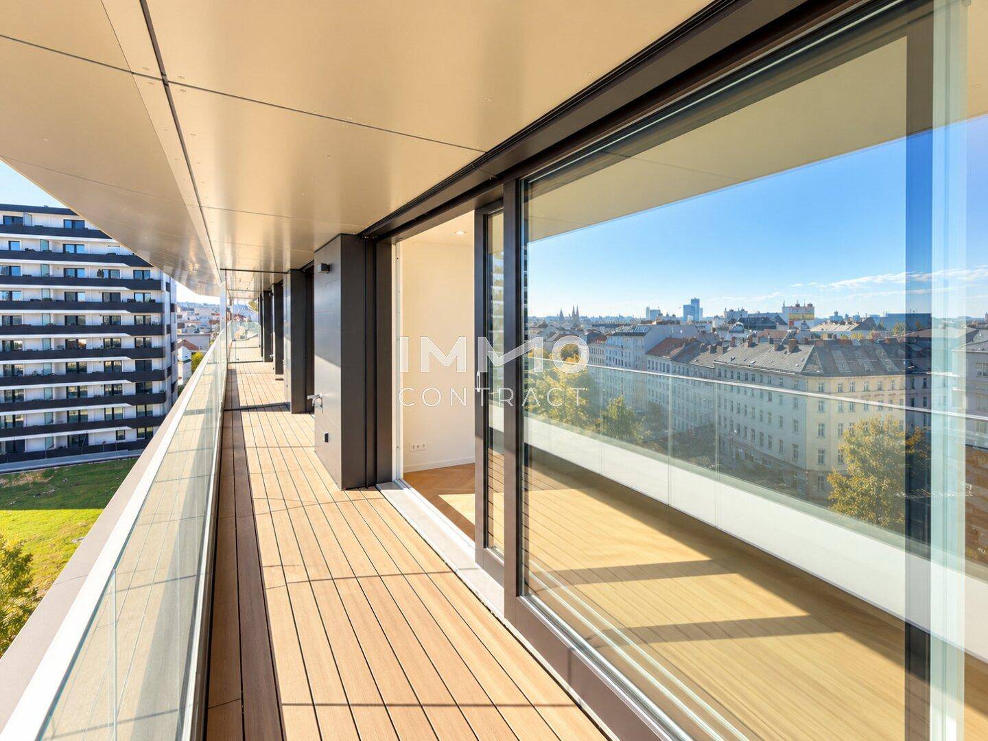 Langer Balkon mit Holzboden und Glasgeländer bietet weiten Stadtblick.