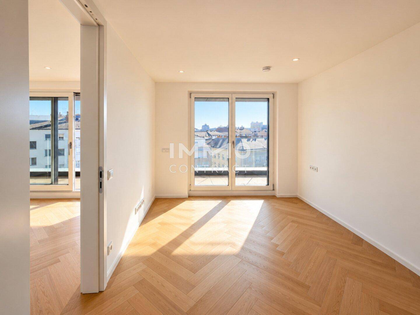 Heller Raum mit Parkettboden und Zugang zu einem Außenbereich mit Stadtblick.