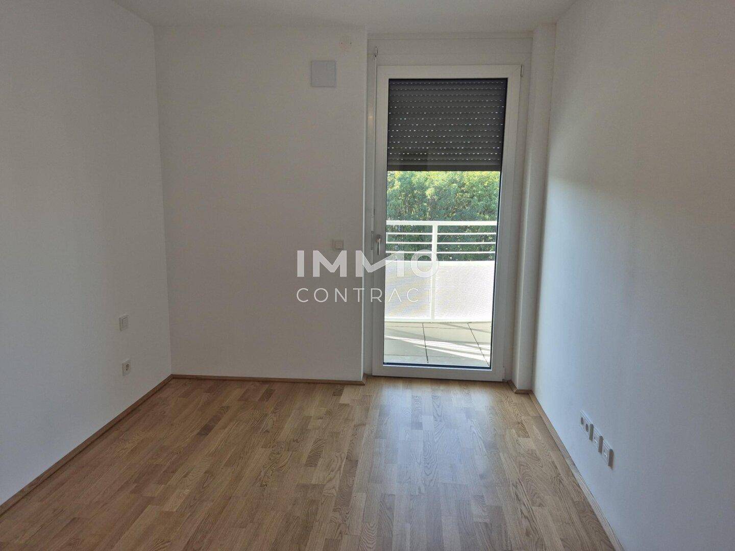 Helles Schlafzimmer mit Parkettboden und direktem Zugang zu einem Balkon, mit Rollladen ausgestattet.