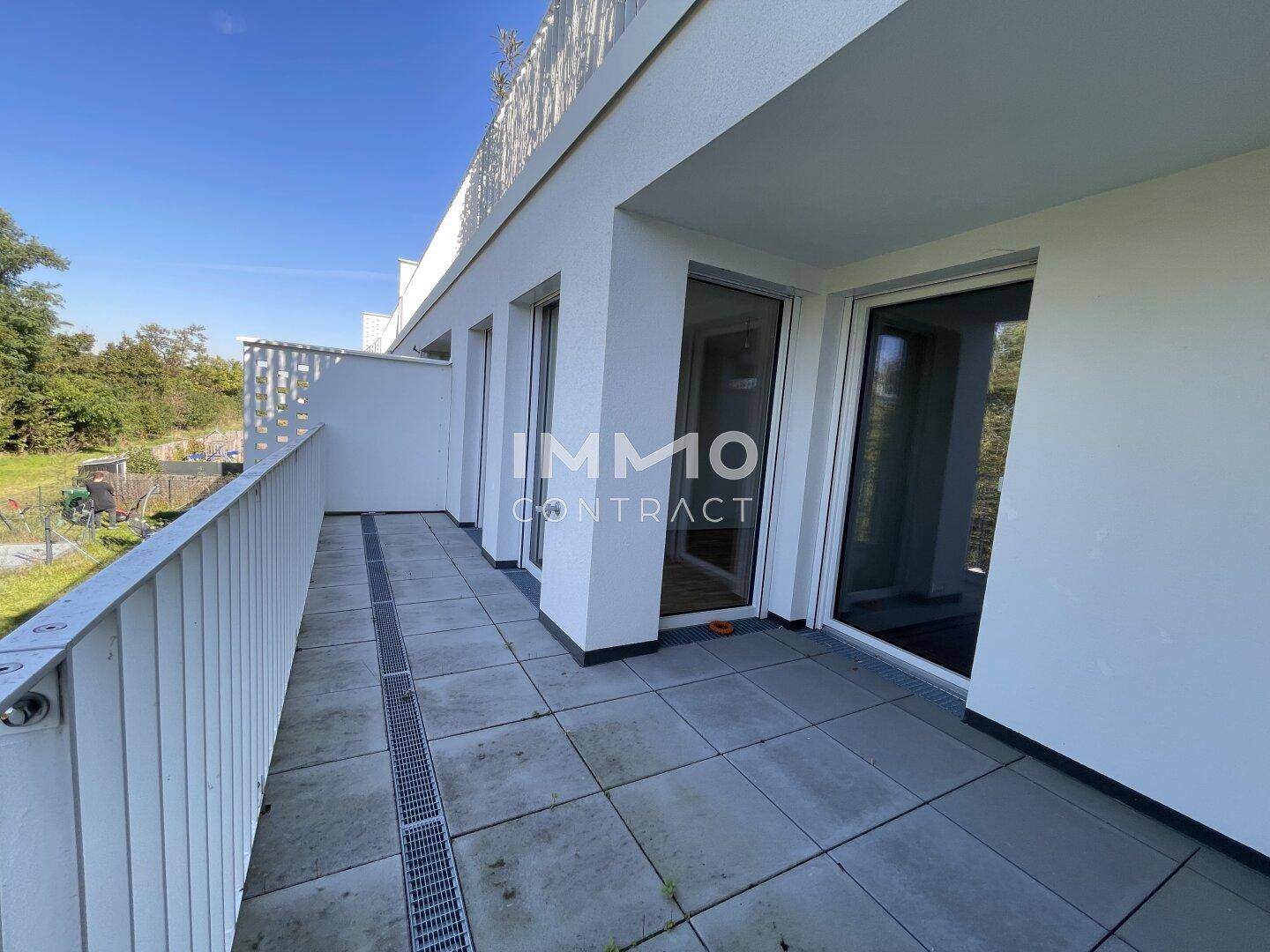 Geräumige, leere Terrasse mit Fliesenboden und moderner Brüstung, bereit zur Gestaltung.