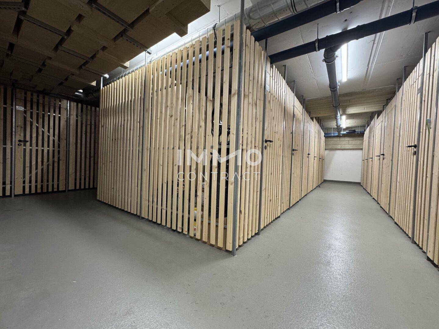 Zahlreiche individuelle Abstellräume mit Holzlamellenwänden im Kellerbereich des Gebäudes.