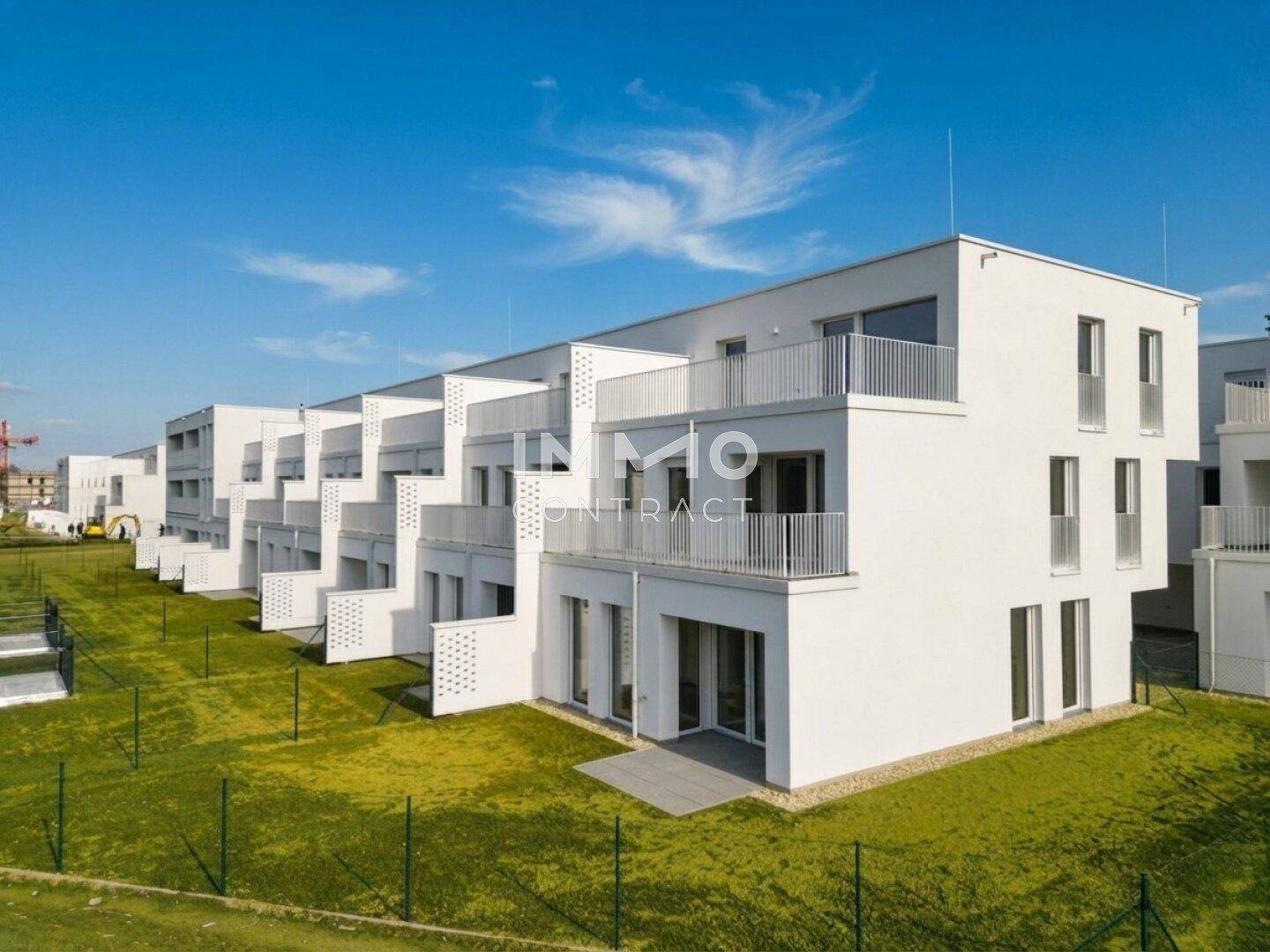 Ansicht einer modernen Wohnanlage mit mehreren Einheiten und grünen Außenbereichen.