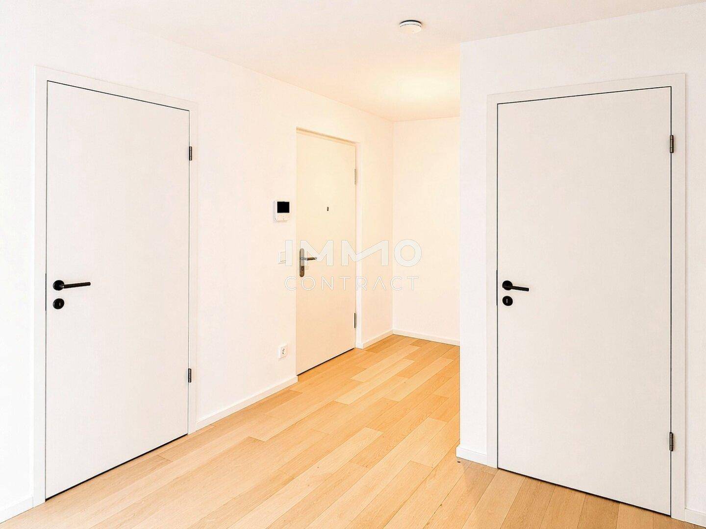 Heller Flur mit Holzboden und modernen weißen Türen, die zu verschiedenen Räumen führen.
