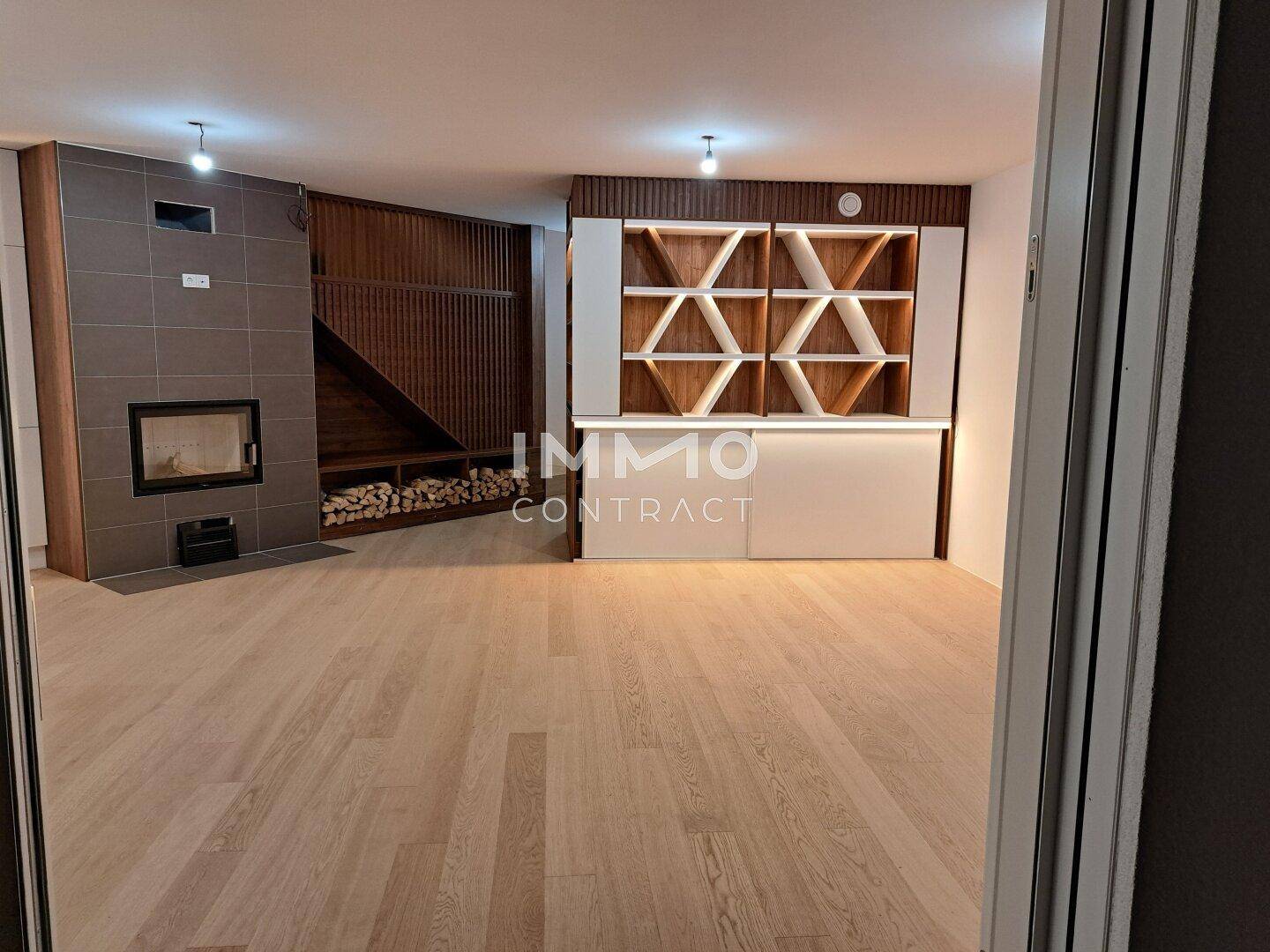 Heller Wohnbereich mit modernem Kamin, integrierter Holzablage und dekorativen Regalelementen.