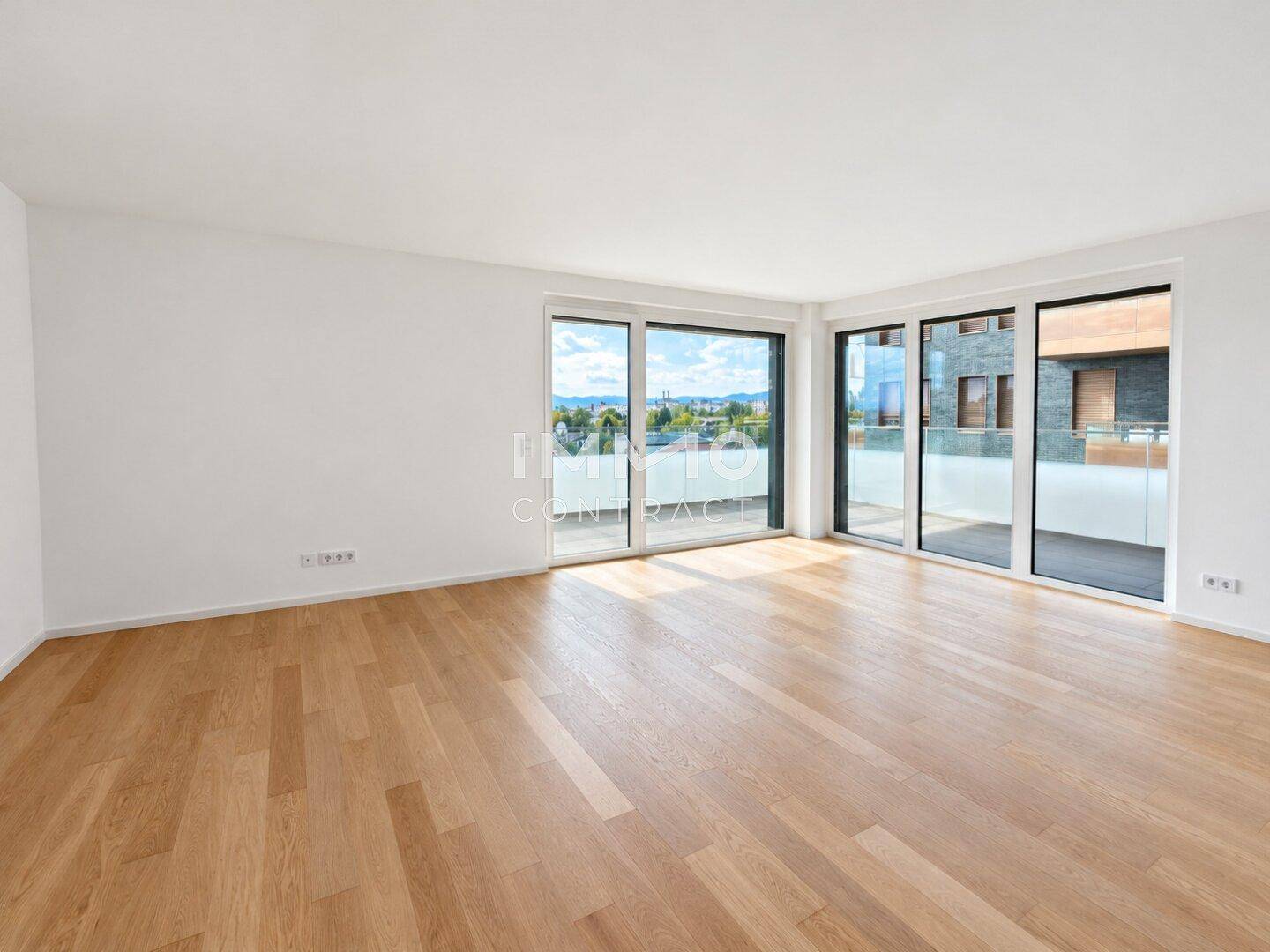 Geräumiges Wohnzimmer mit hellen Holzböden und bodentiefen Fenstern mit Stadtblick.
