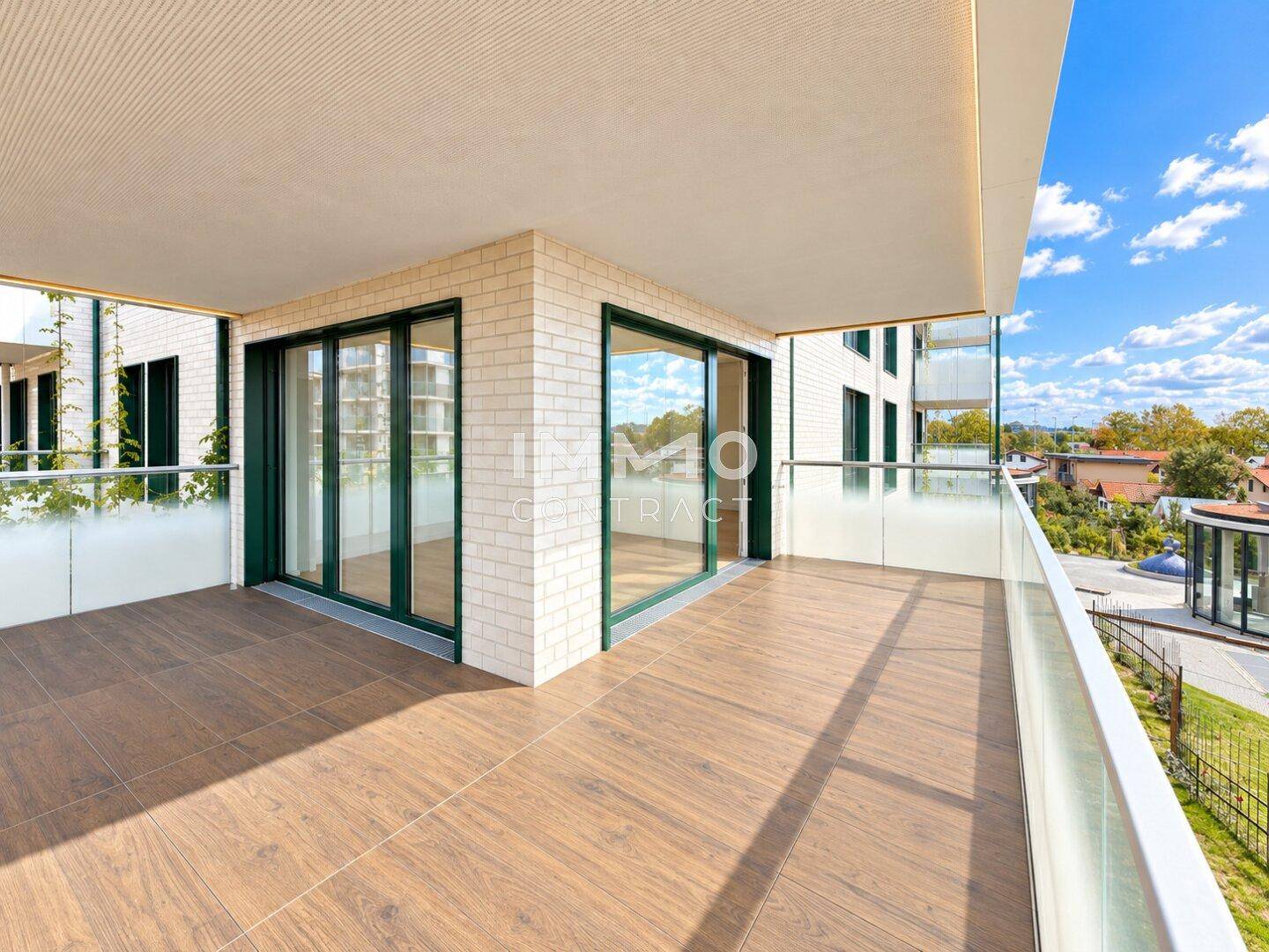 Geräumiger Balkon mit Fliesenboden und Glasgeländer, ideal für entspannte Stunden im Freien.