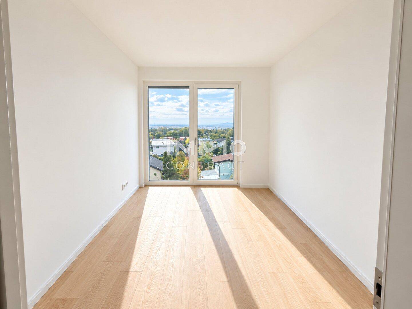 Schlafzimmer mit hellem Parkettboden und großen Fenstern, die einen weiten Blick bieten.