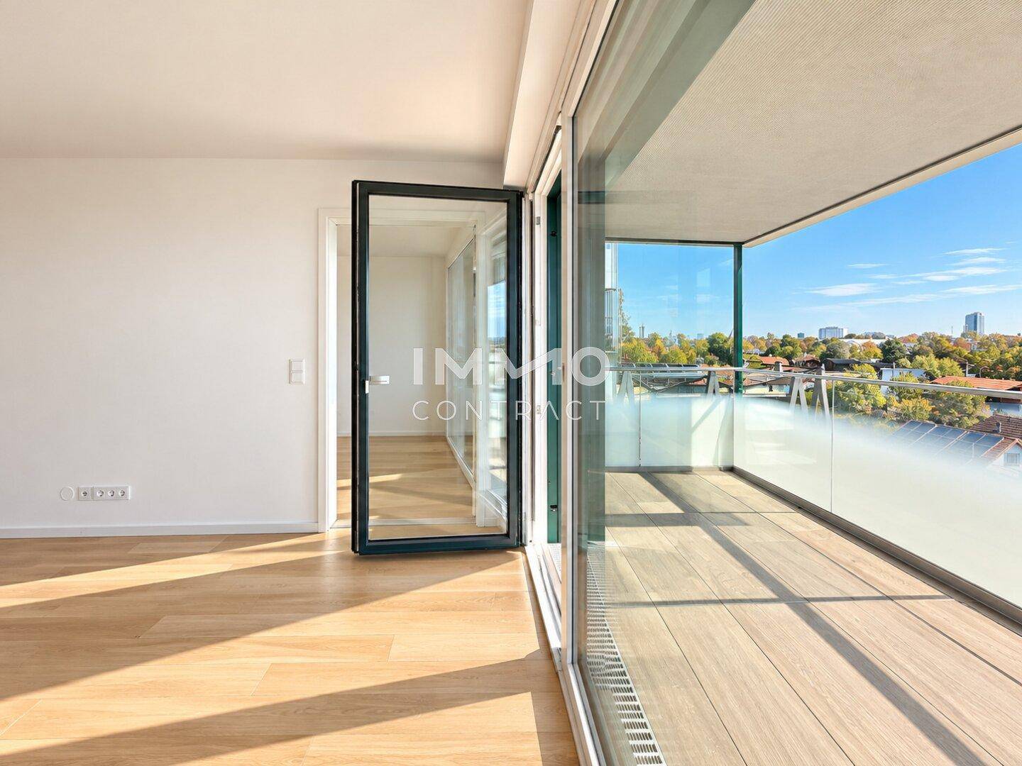 Heller Wohnbereich mit Holzboden und Zugang zu einem sonnigen Balkon mit Stadtblick.