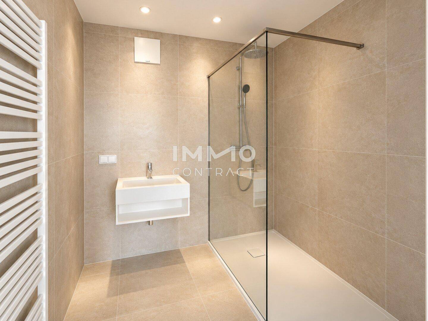 Modernes Badezimmer mit begehbarer Dusche, Wandwaschbecken und beigefarbenen Fliesen.