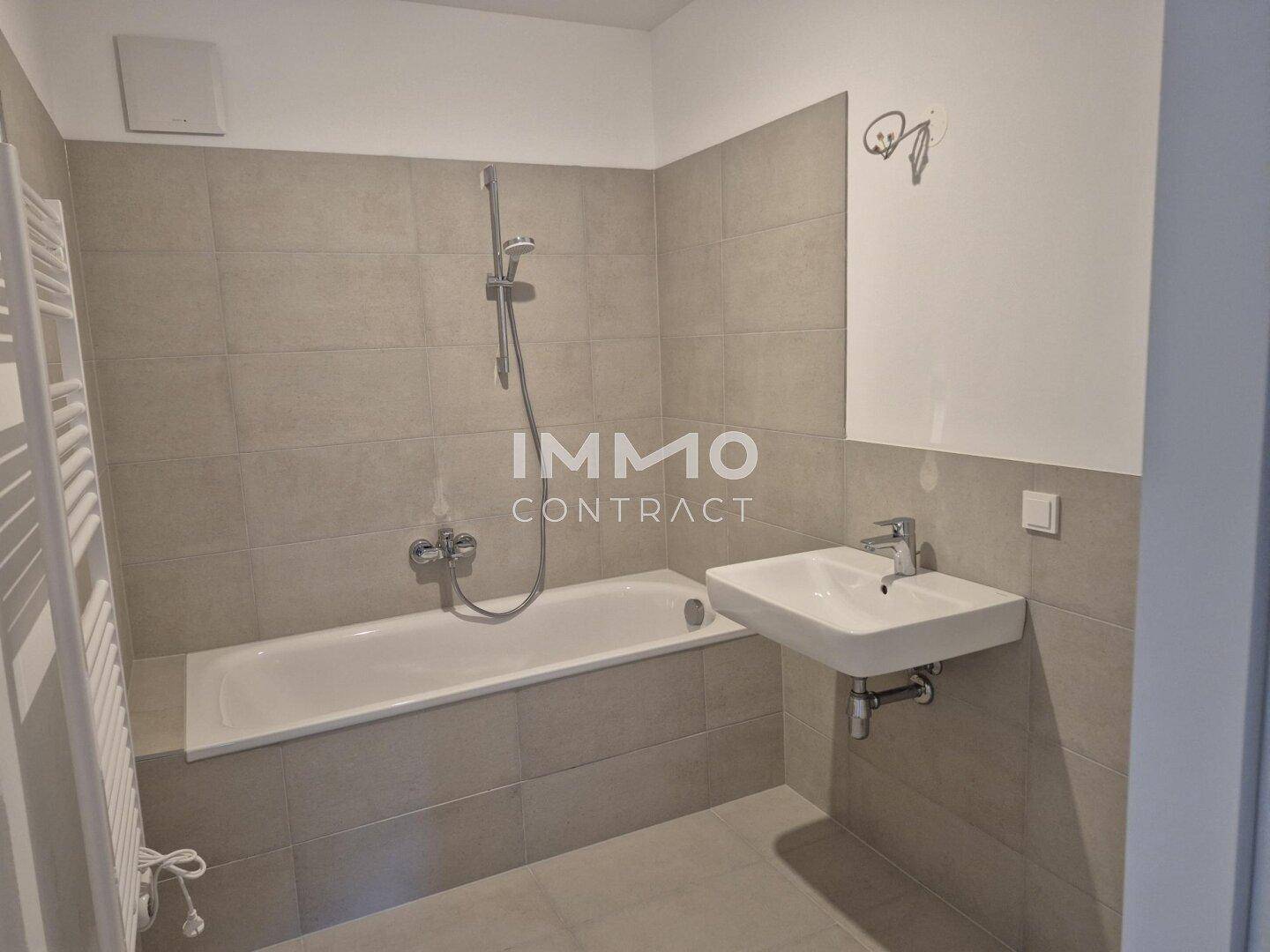 Modernes Badezimmer mit Badewanne, Einzelwaschbecken und beheiztem Handtuchhalter.