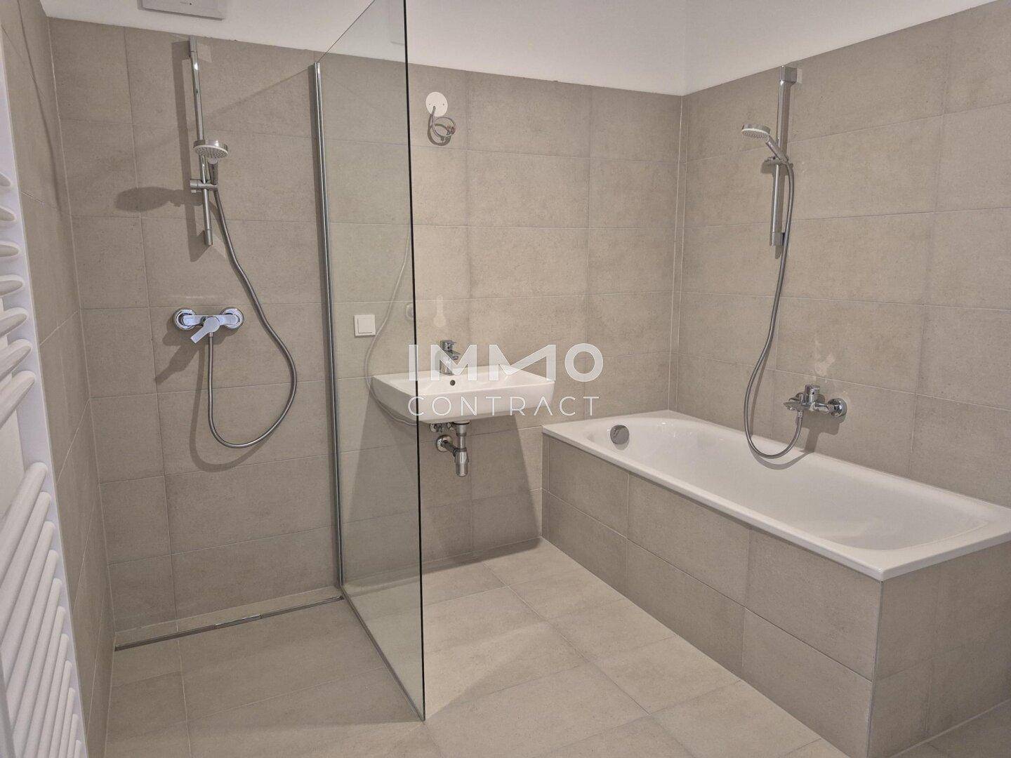 Modernes Badezimmer mit Badewanne, ebenerdiger Dusche und Einzelwaschbecken in hellen Grautönen.