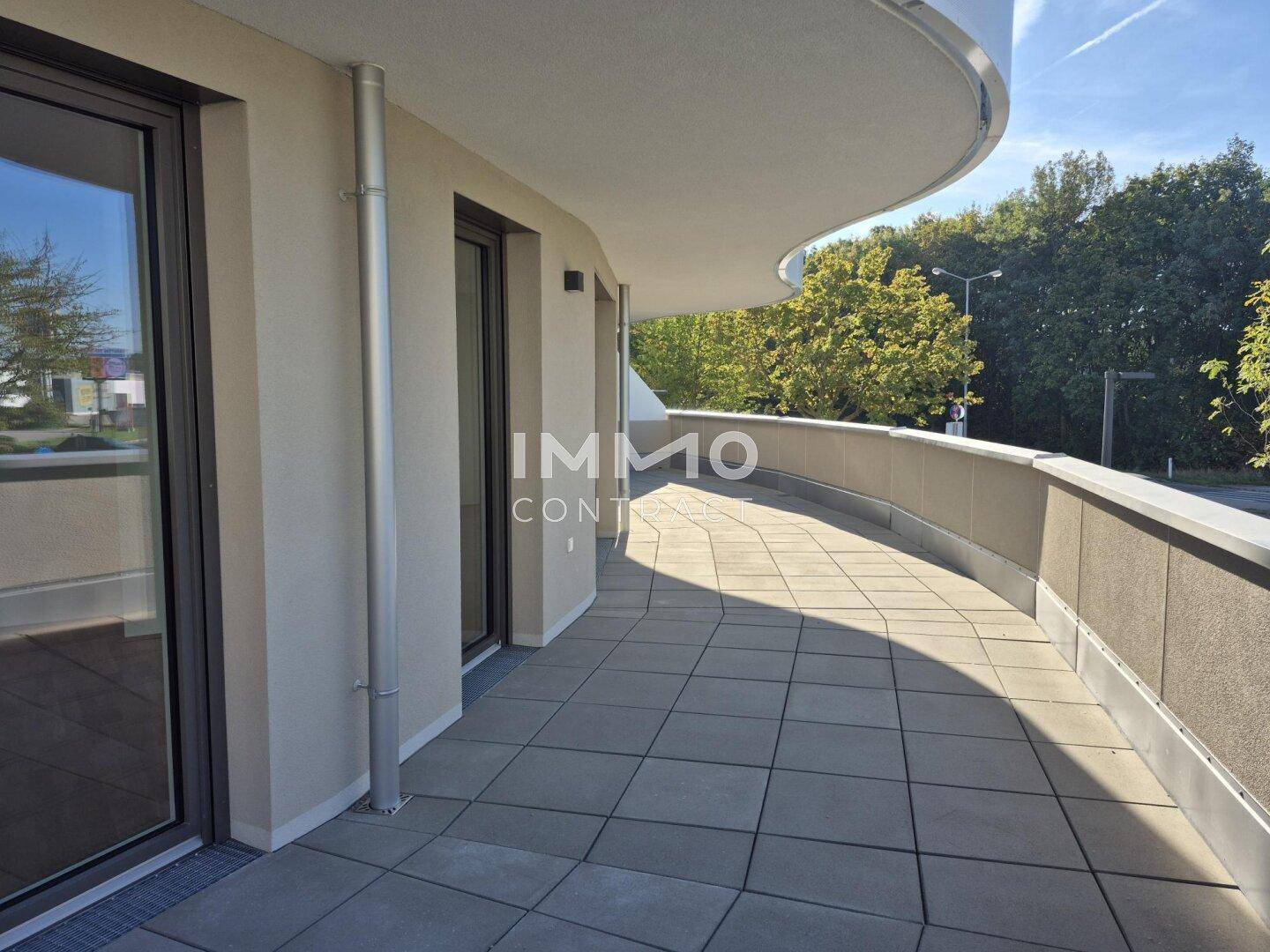 Langer, geschwungener Balkon mit Fliesenboden und Blick ins Grüne, ideal zum Entspannen.