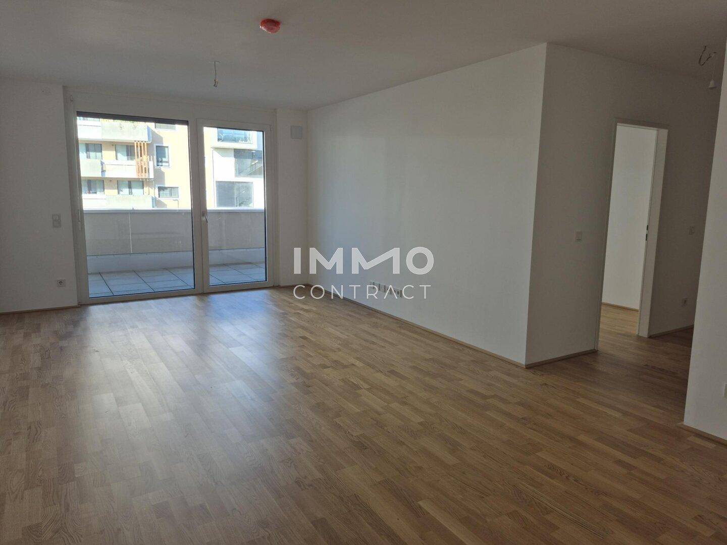 Geräumiges, helles Wohnzimmer mit Parkettboden und großzügigem Zugang zum Balkon.