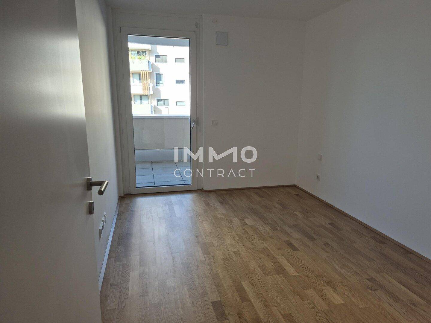 Schlafzimmer mit Parkettboden und Balkonzugang, das viel natürliches Licht hereinlässt.
