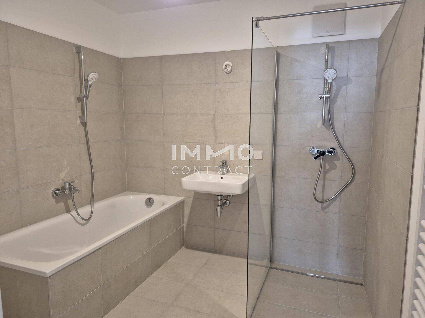 Modernes Badezimmer mit Badewanne, separater Dusche und hellen Fliesen an Wänden und Boden.