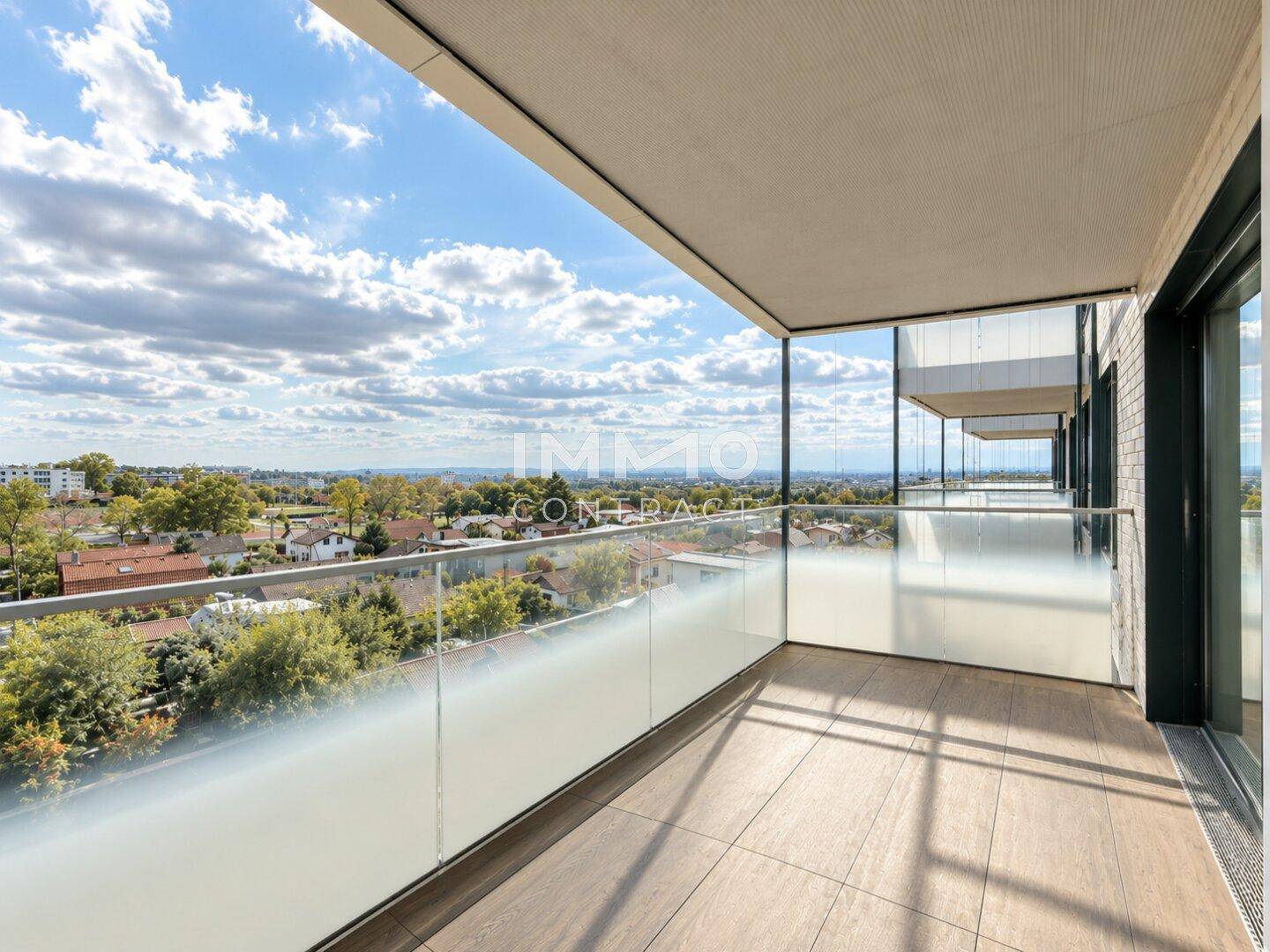 Geräumiger Balkon mit Glasgeländer und weitem Blick über die Stadt und die umliegende Landschaft.