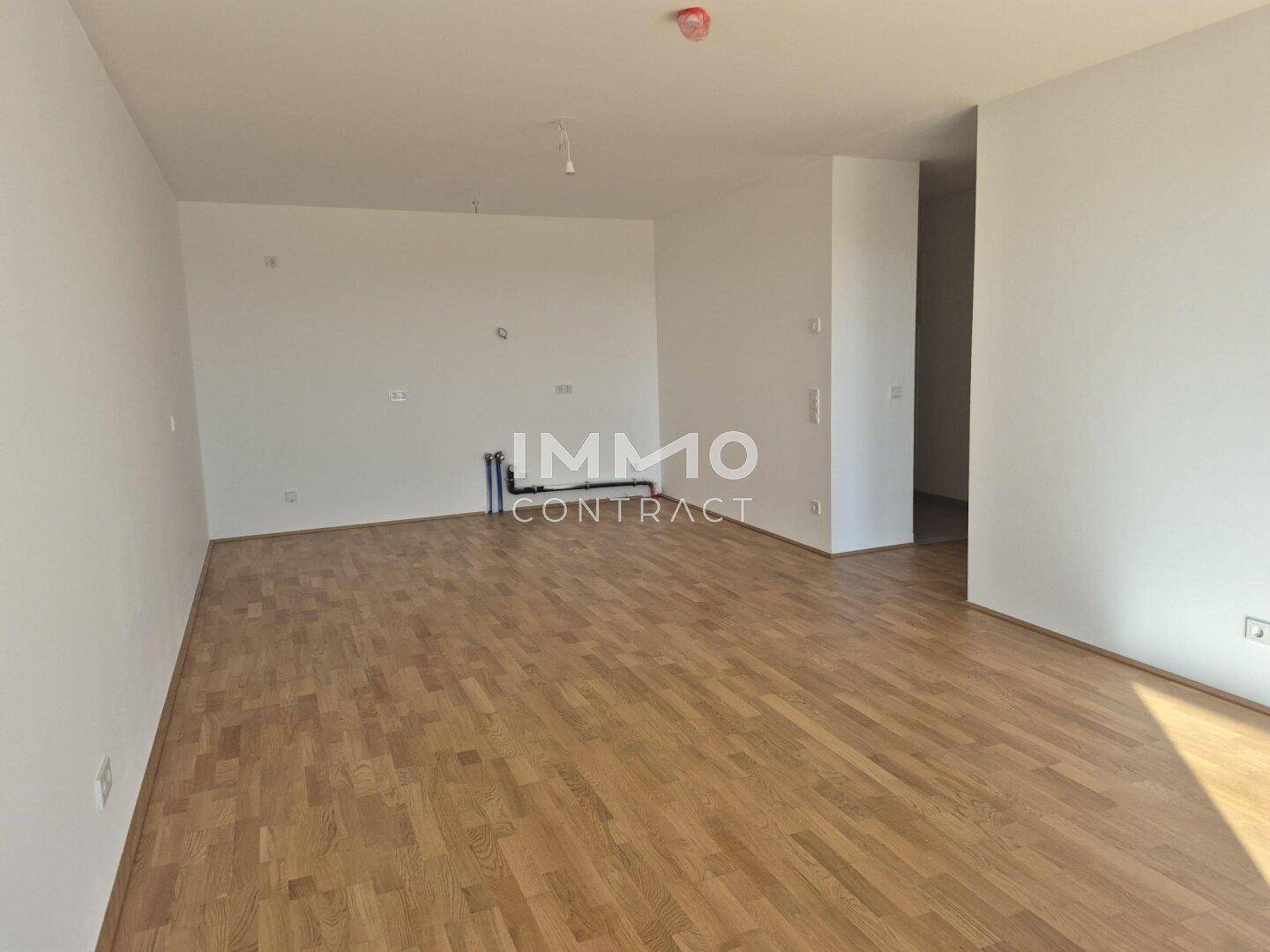 Geräumiger, leerer Wohnbereich mit hellem Parkettboden und weißen Wänden, bereit zur Gestaltung.