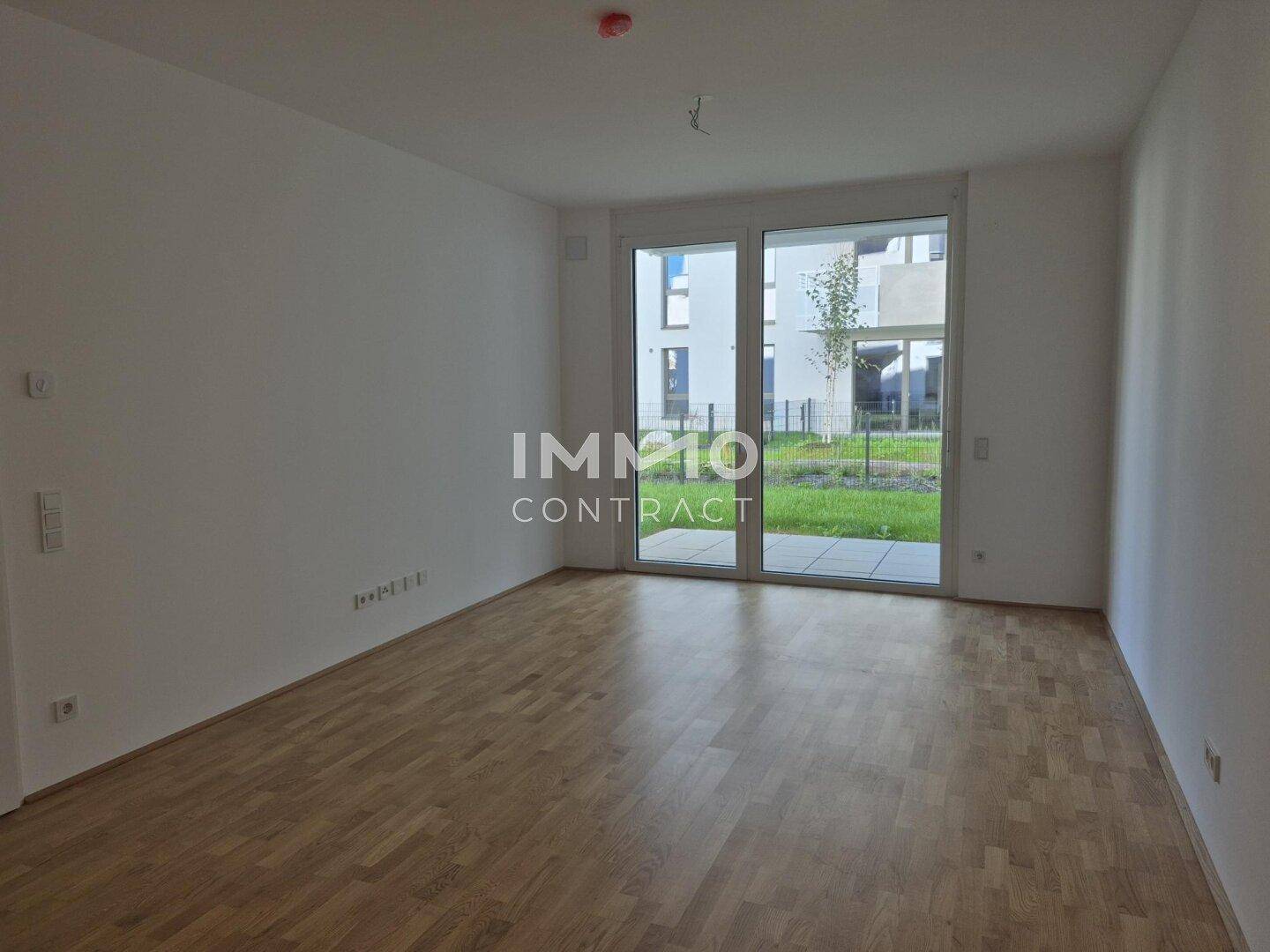 Heller Wohnraum mit Parkettboden und großen Glastüren zum Gartenbereich.
