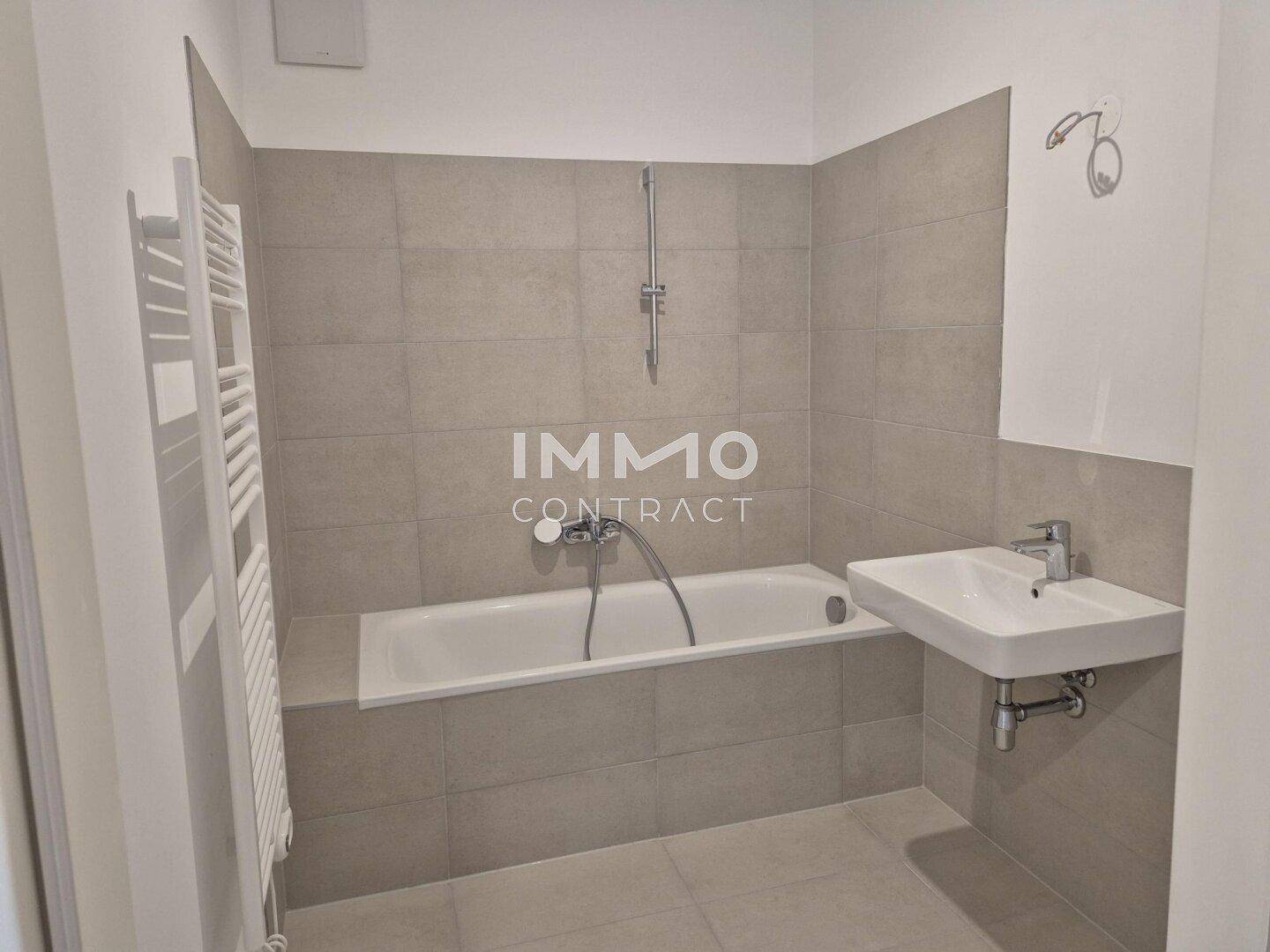 Modernes Badezimmer mit Badewanne, Waschbecken und beheiztem Handtuchhalter.