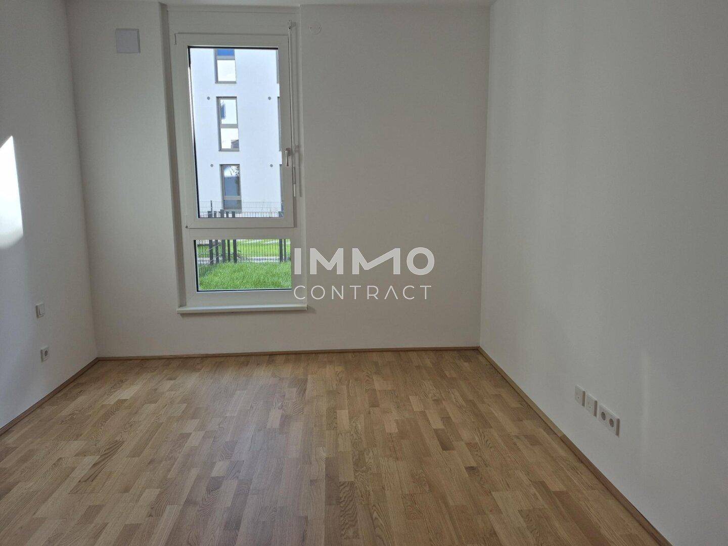 Helles Schlafzimmer mit Parkettboden und Fenster mit Blick auf die Umgebung.