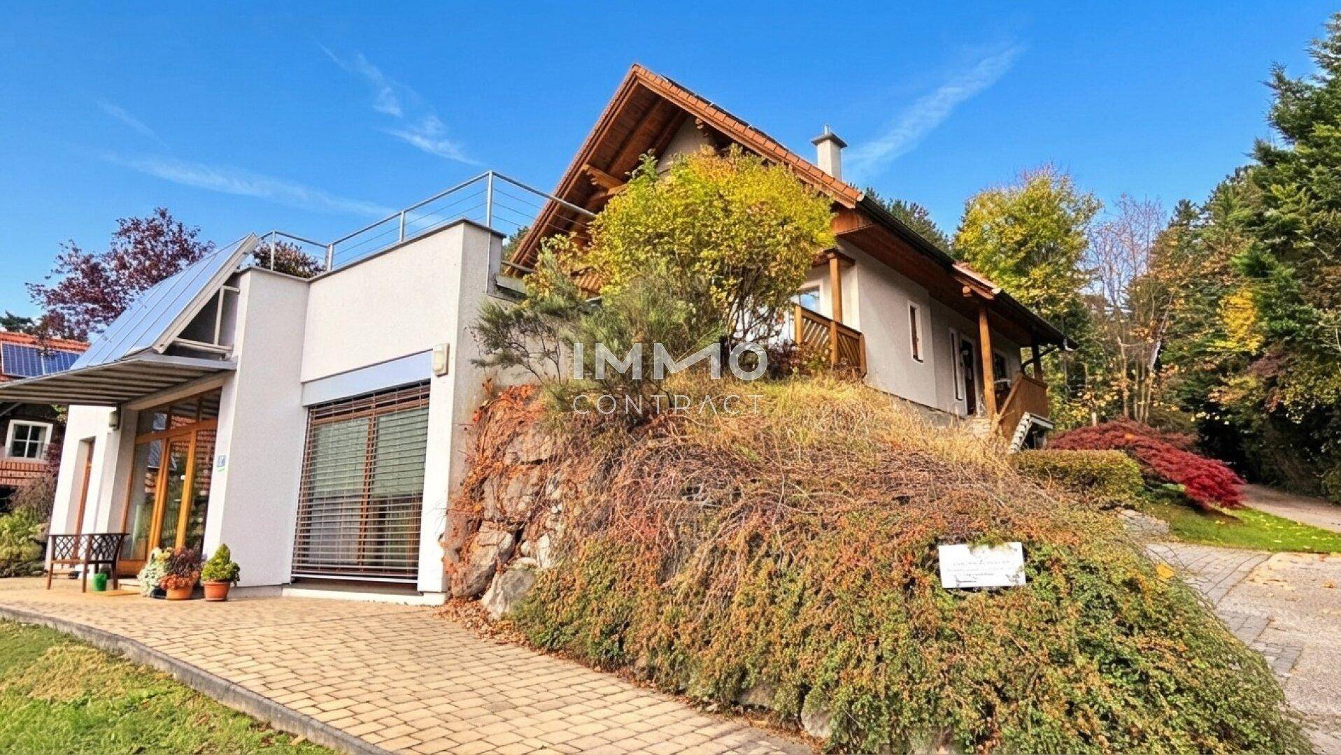 Modernes Haus mit Solarpaneelen und gepflegter Außenanlage in Hanglage.