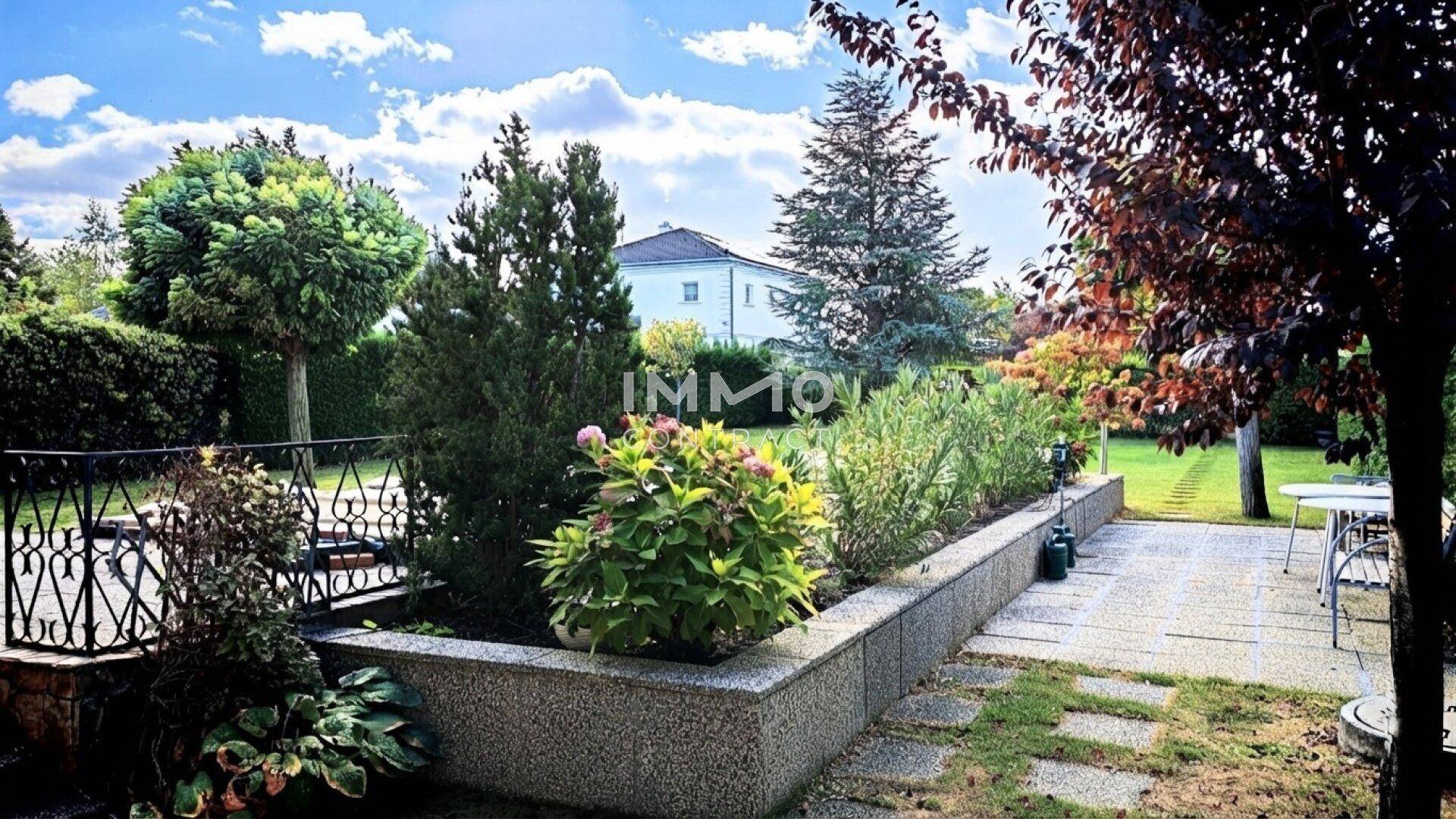 Gepflegter Gartenbereich mit Blumenbeeten, Sträuchern und Sitzgelegenheit.