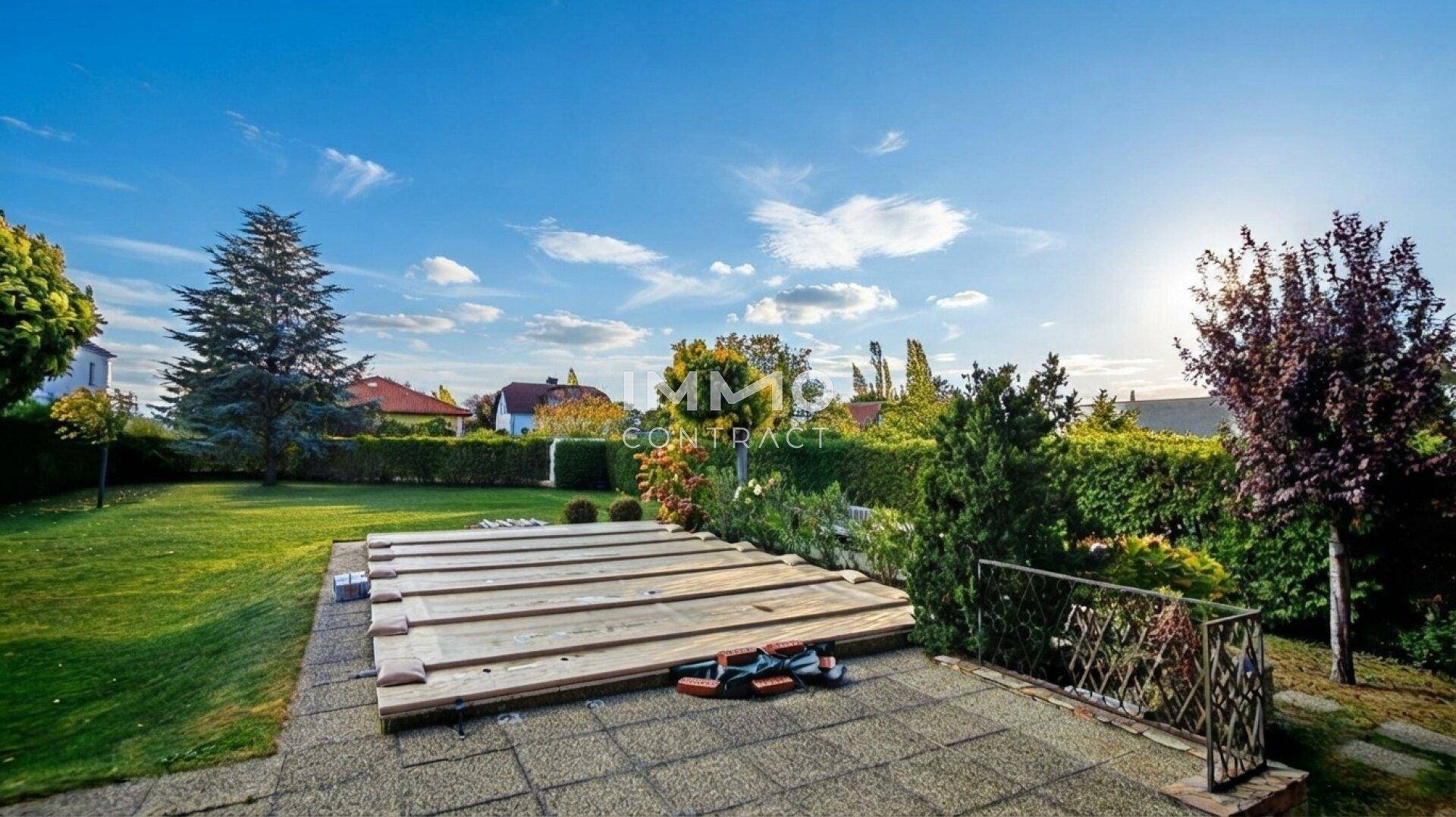 Weitläufiger Garten mit großer Rasenfläche und einer Abdeckung, möglicherweise für einen Pool.